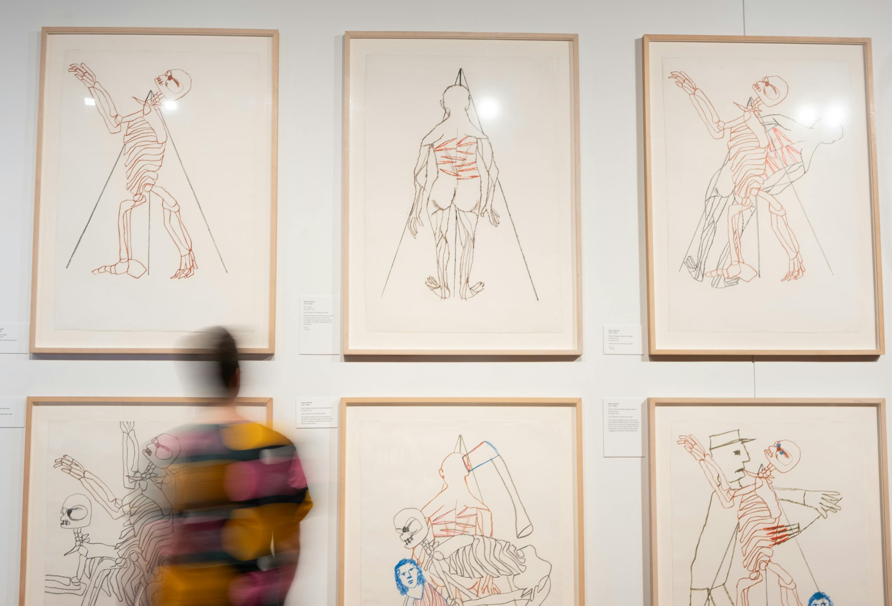 Person examines artworks by Sidney Nolan in For the Term of His Natural Life exhibition