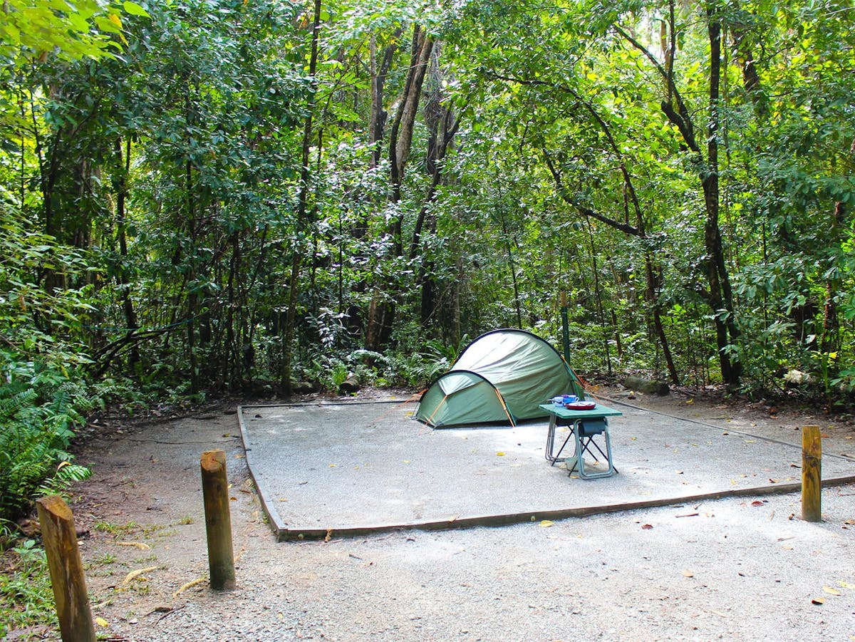 small tent and table set-up in campsite surrounded by forest
