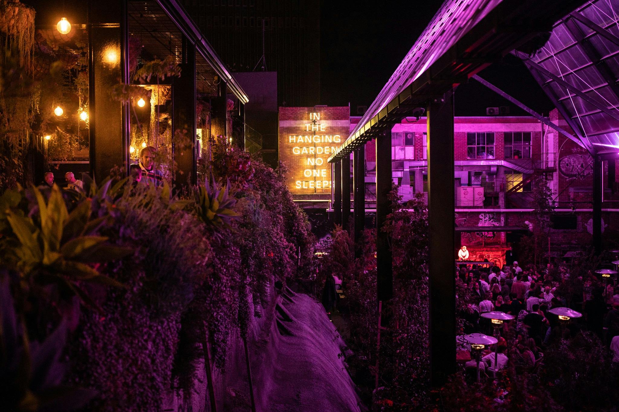 A picture of In The Hanging Garden at night with a sign visible