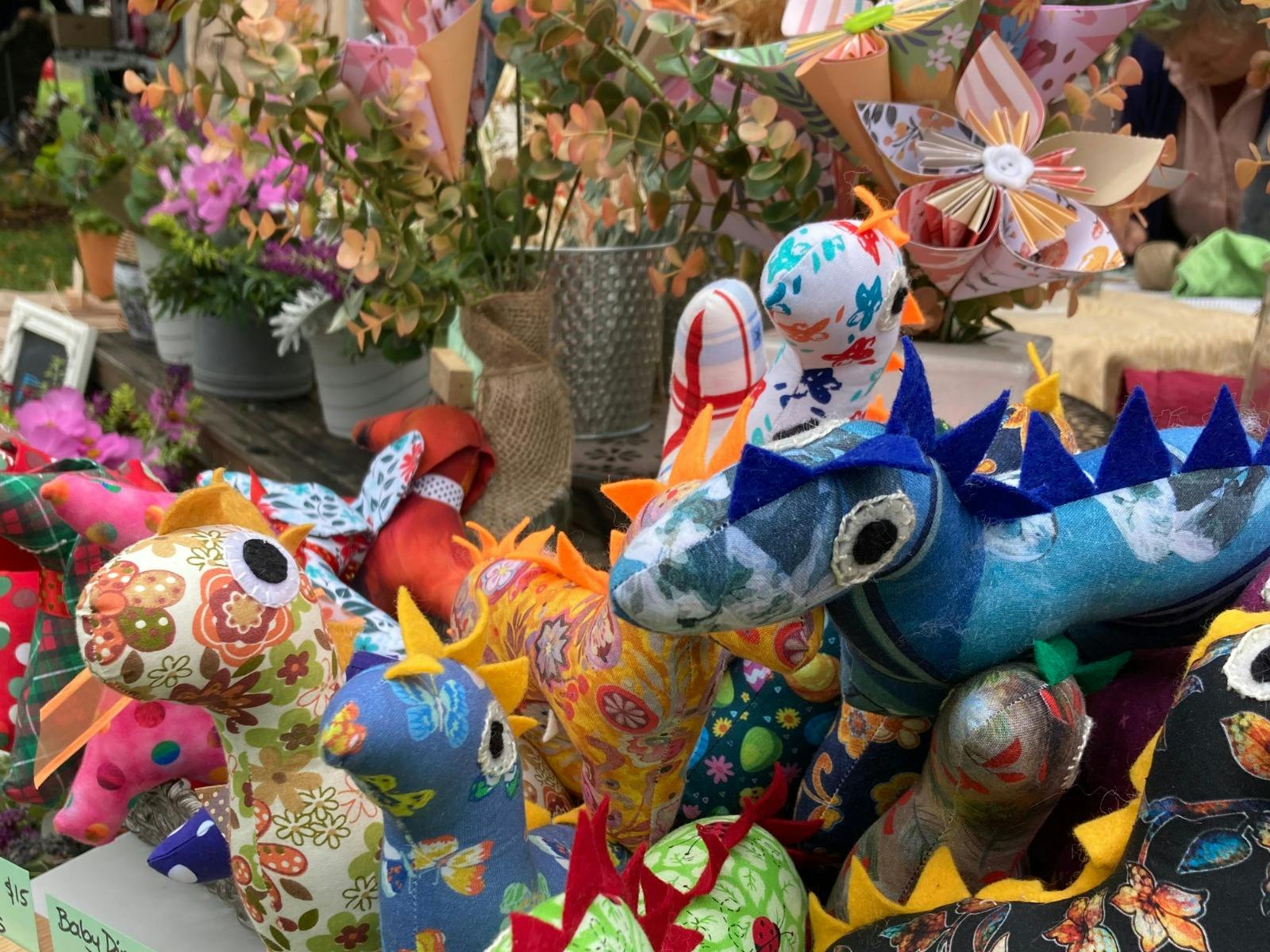 Table of craft items - soft stuffed toy dinosaurs, flowers made from paper, etc