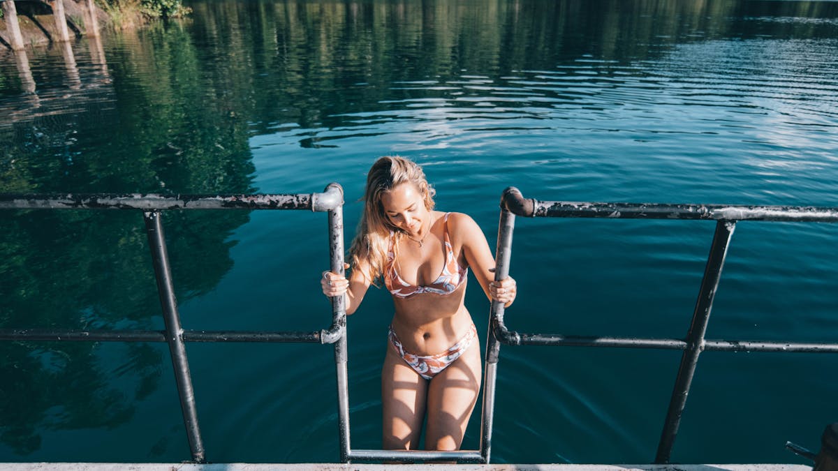 Woman in swimsuit climbing up ladder of diving dock at Lake Eacham in Tropical North Queensland