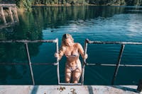 Woman in swimsuit climbing up ladder of diving dock at Lake Eacham in Tropical North Queensland