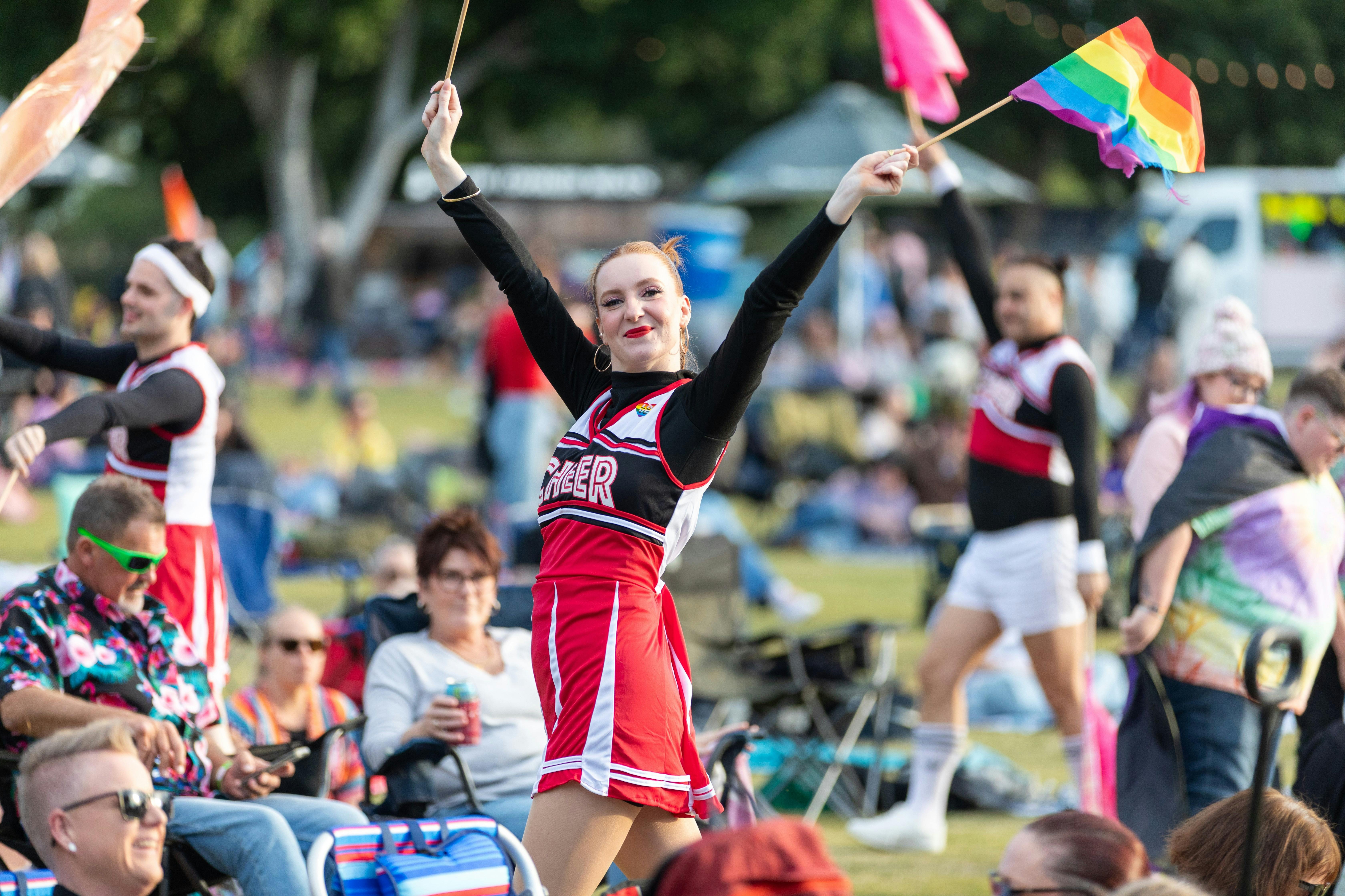 A cheerleader in a red, black, and white uniform performs energetically at Moreton Bay PrideFest, sm