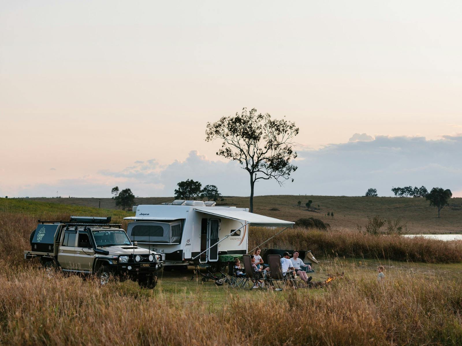 A family sitting in camp chairs in front of their caravan