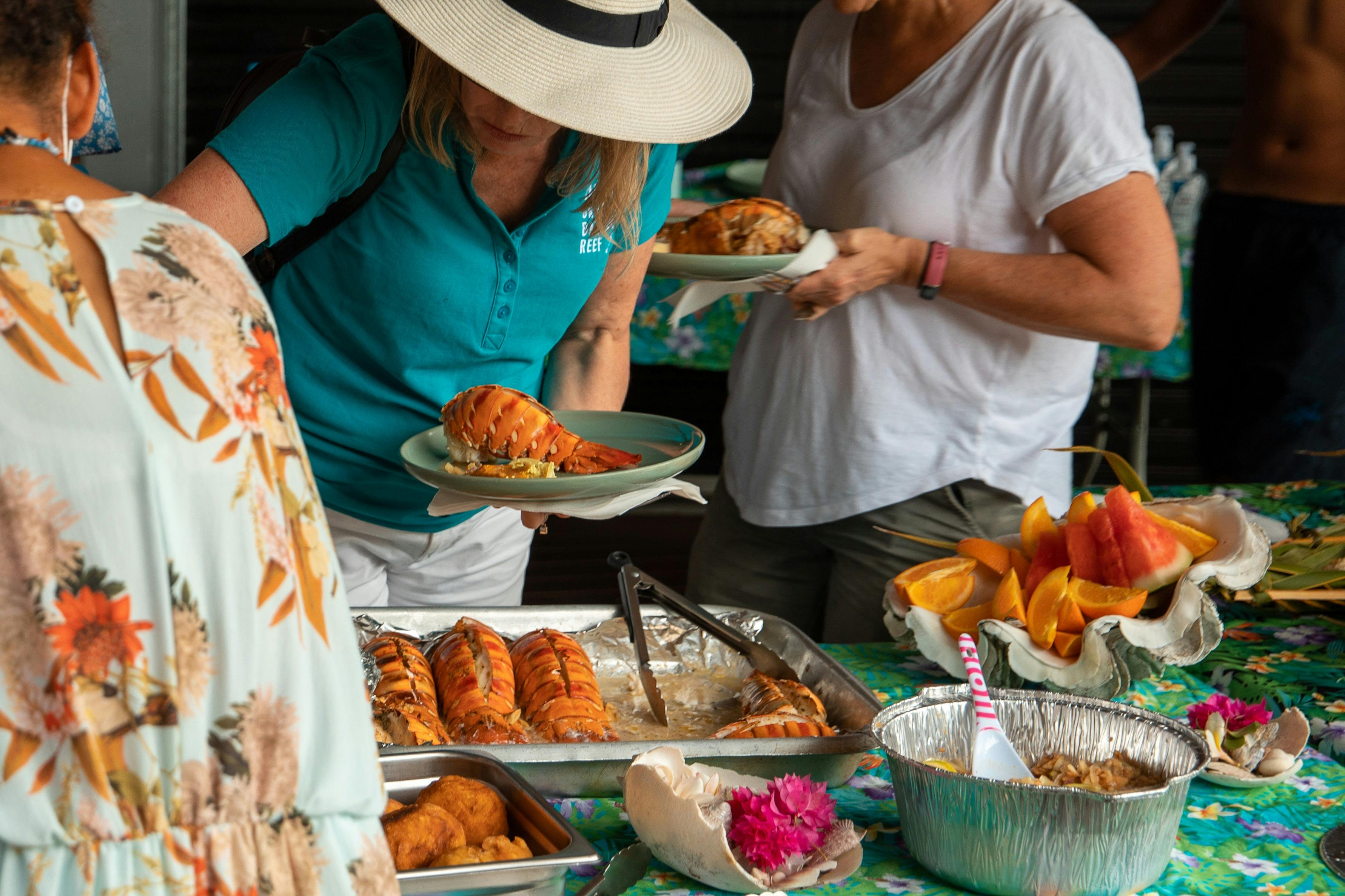 Visitors enjoying a Torres Strait seafood buffet with fresh lobster, tropical fruit and local cuisin