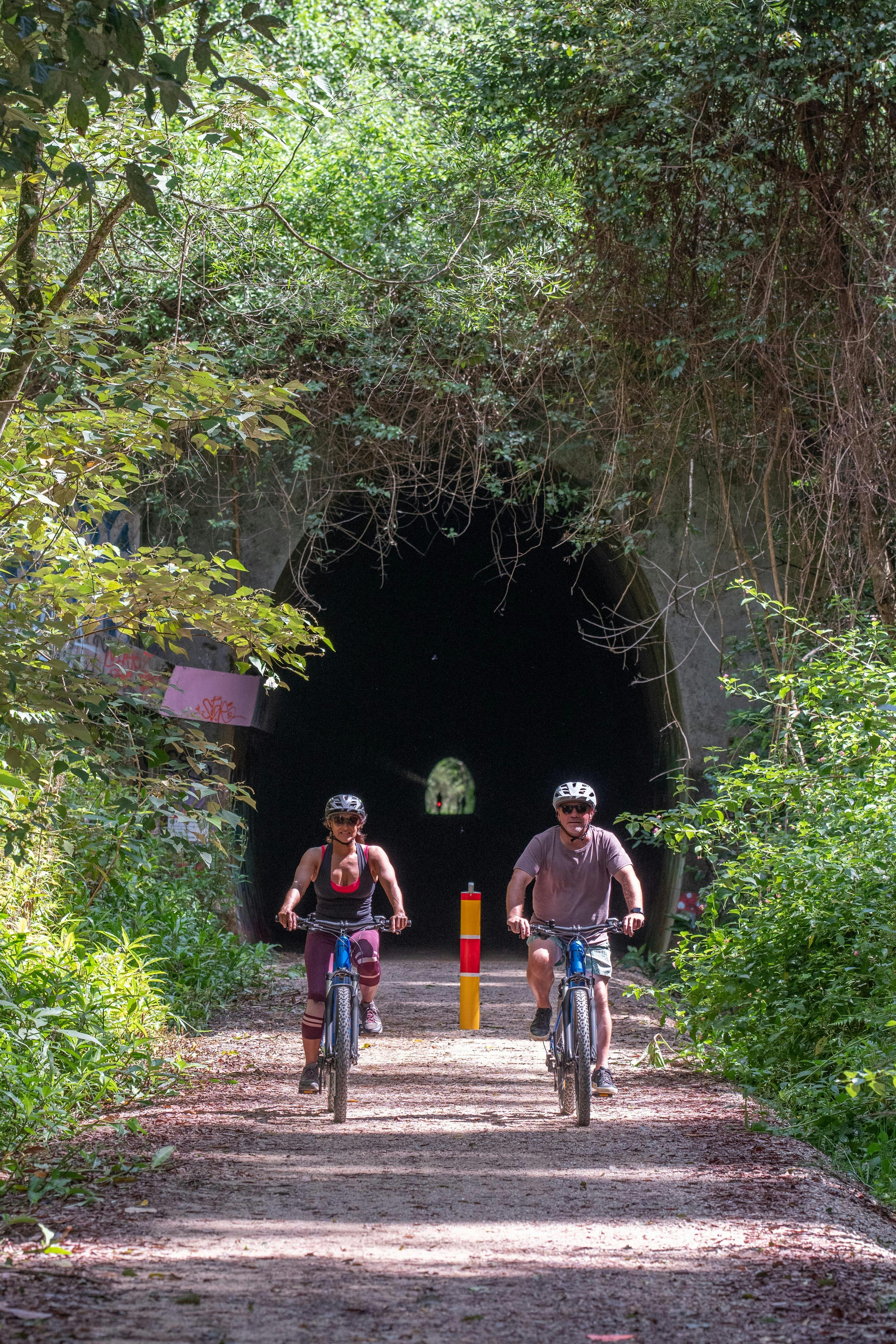 Two riders on ebikes in front of railway tunnel