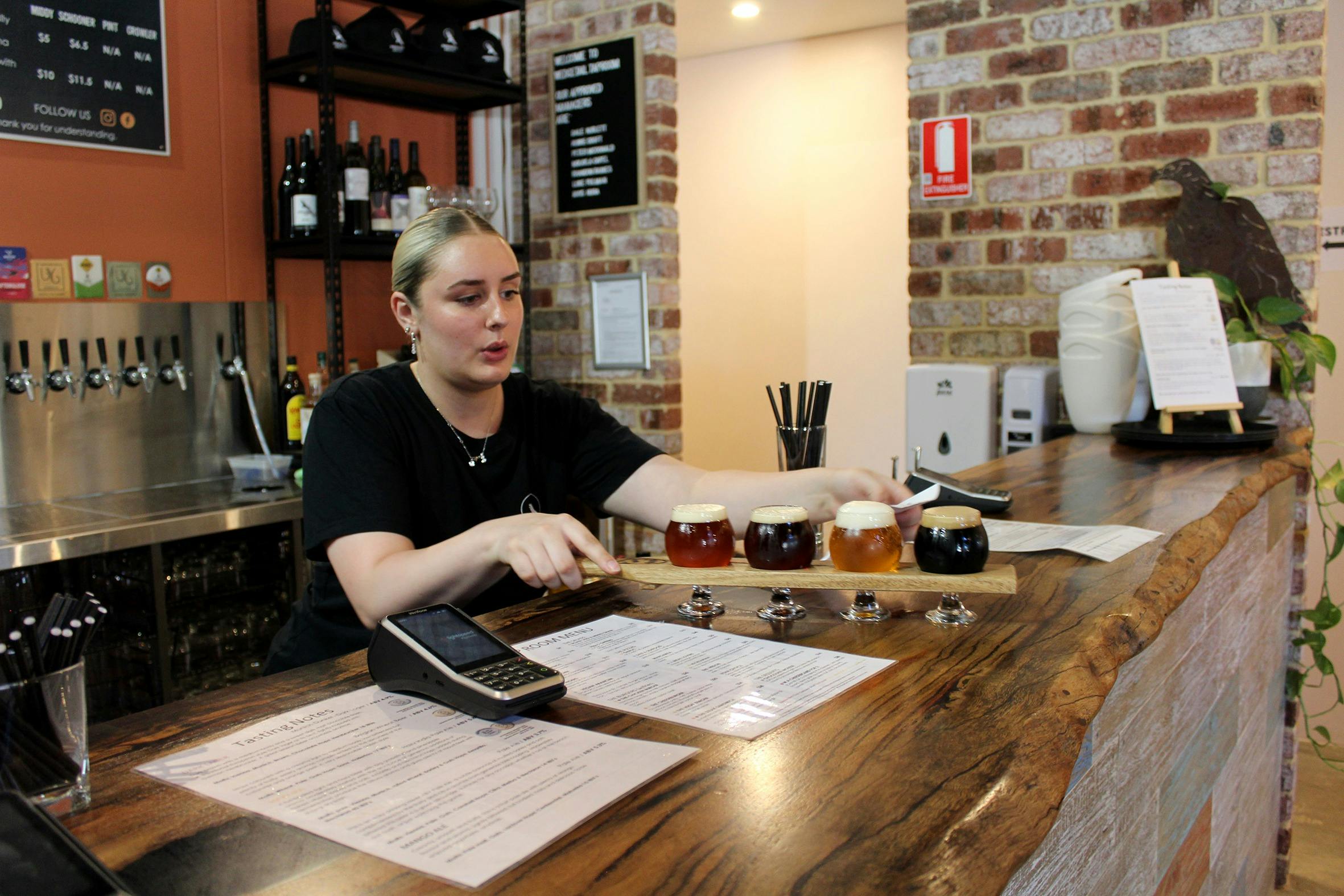 Girl serving a Beer Paddle with an assortment of beers.