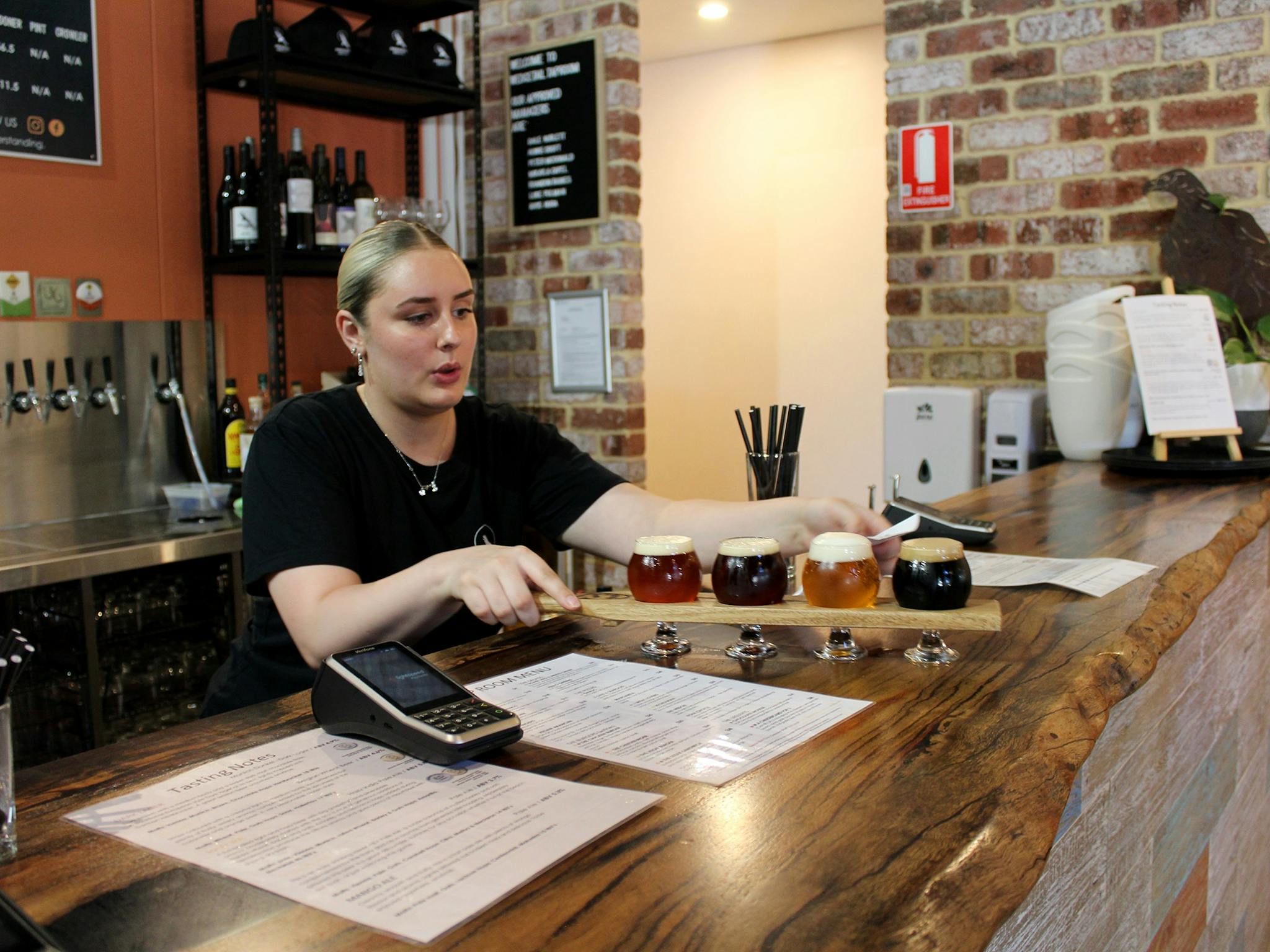 Girl serving a Beer Paddle with an assortment of beers.