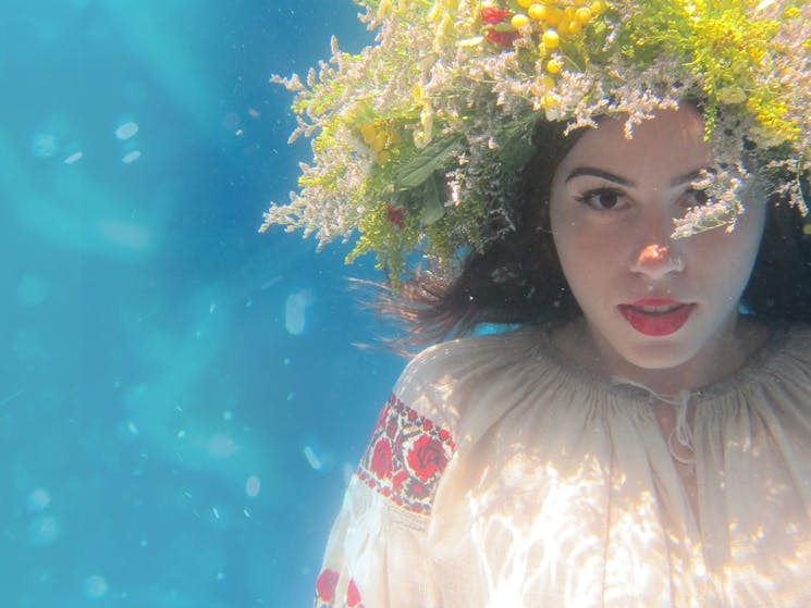 A Ukrainian girl looks towards the camera, floating underwater.