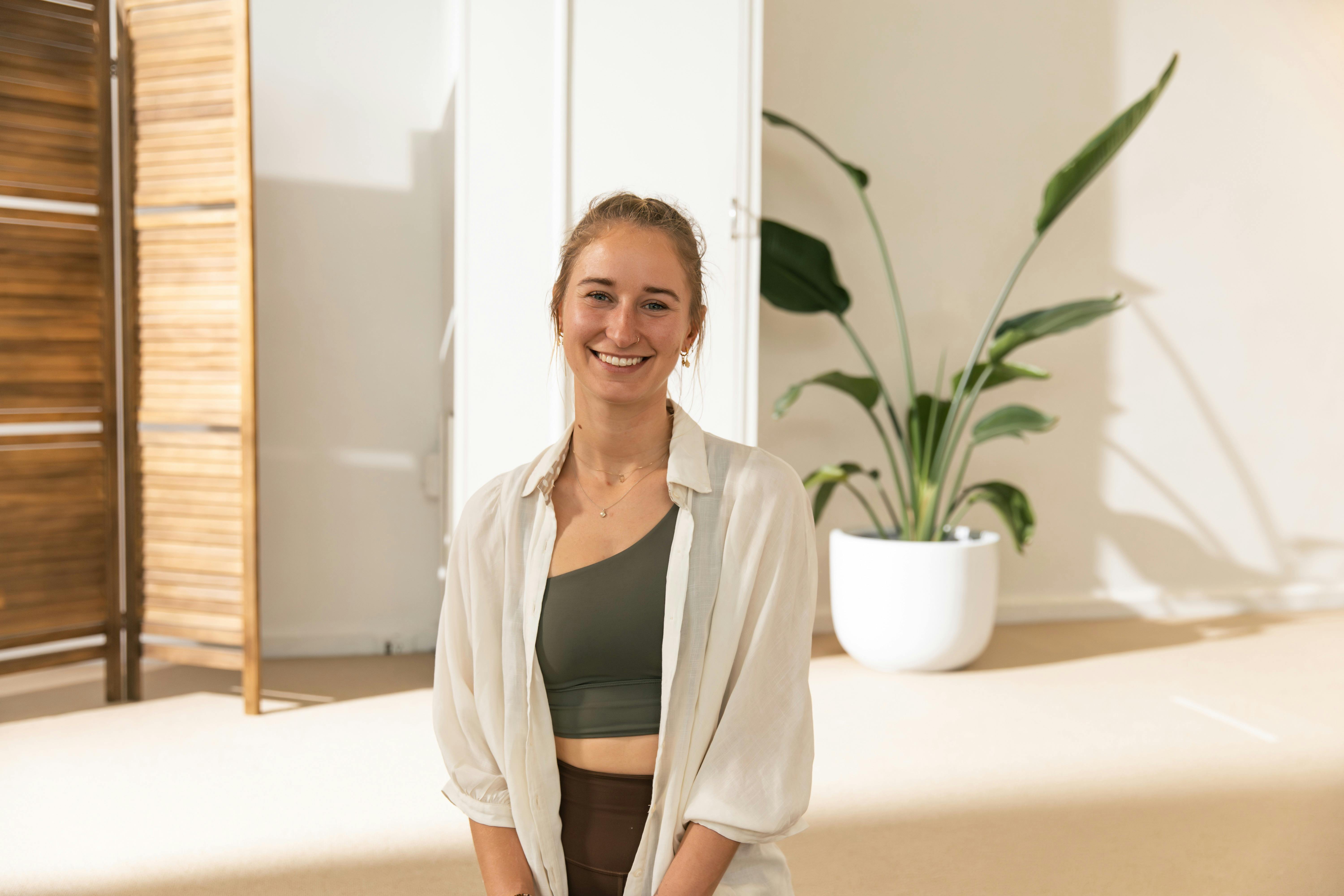 Olivia is bright faced and standing in a pilates studio
