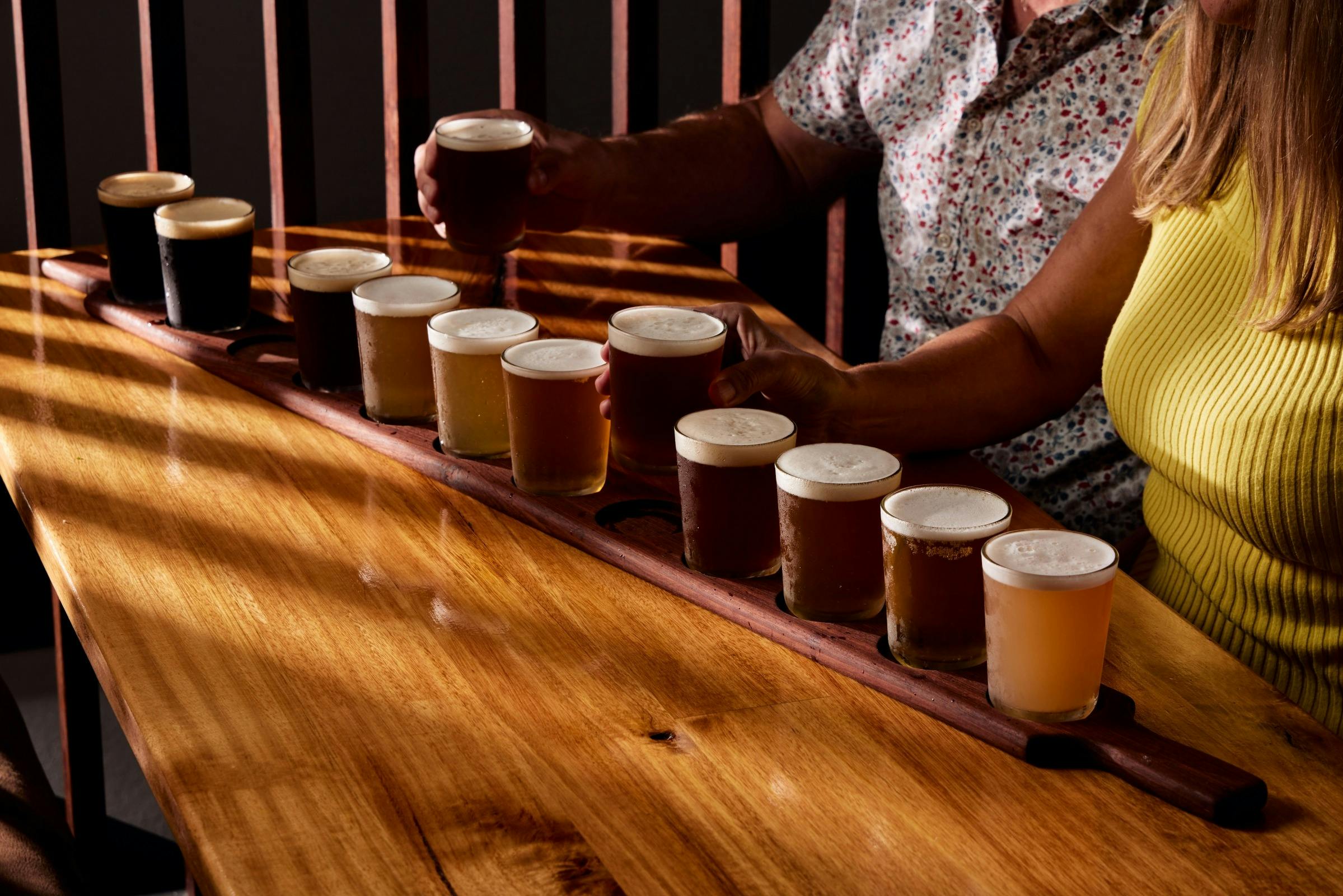 2 people drinking a beer paddle with 12 beers on it