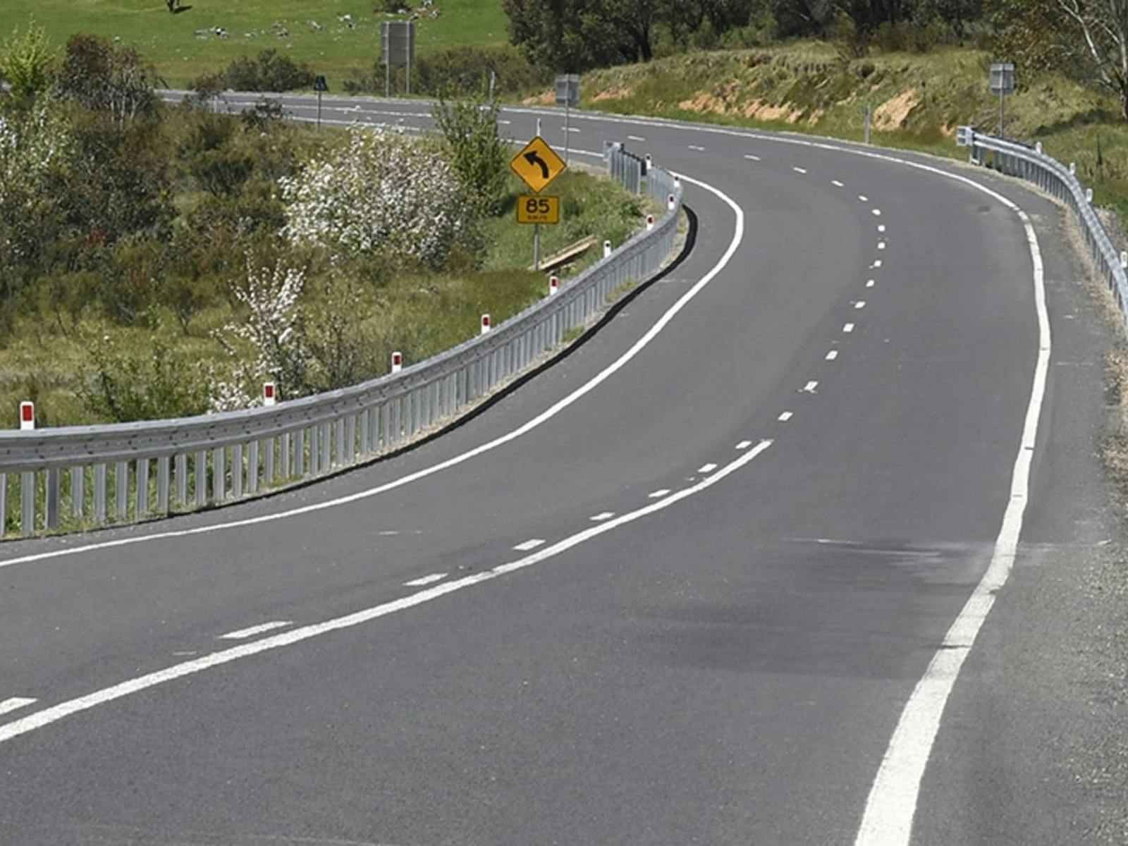 A curved road with wildflowers in the Snowy Mountains
