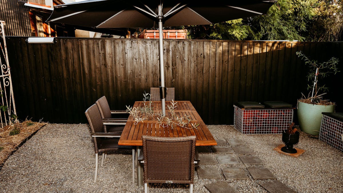 Black fenced courtyard with gravel and pavers, a fire pit, and dinig setting