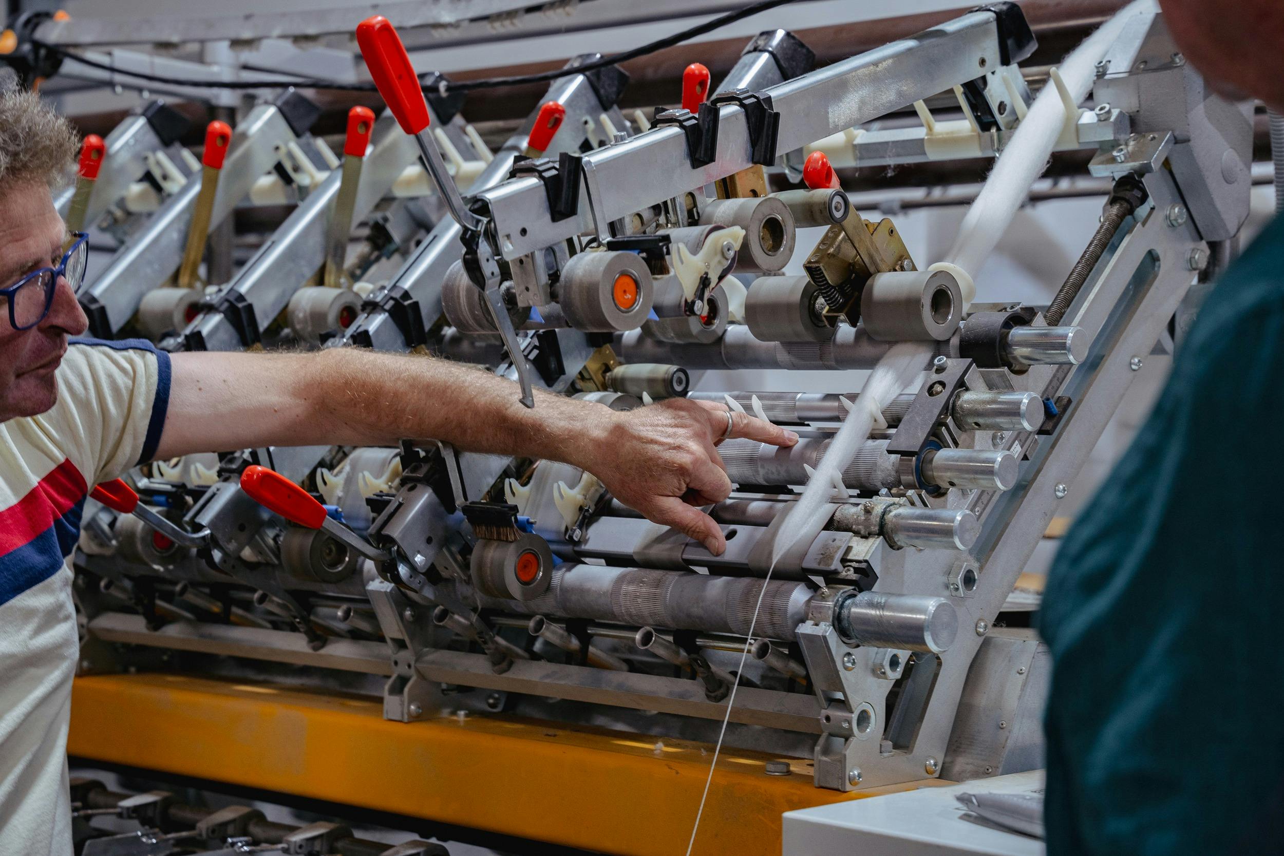 A hand is pointing at a roving just before it gets spun