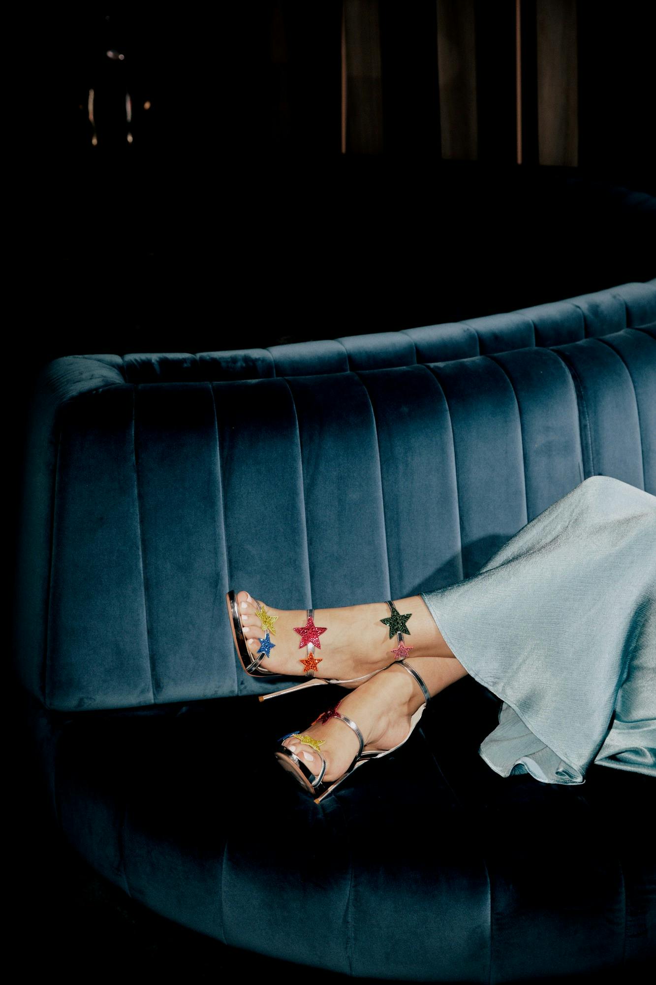 Persons high heels with stars on it resting on a velvet lounge
