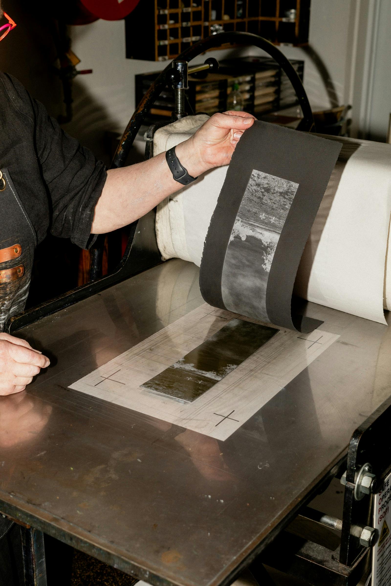 A photograph of hands peeling a print off of a press