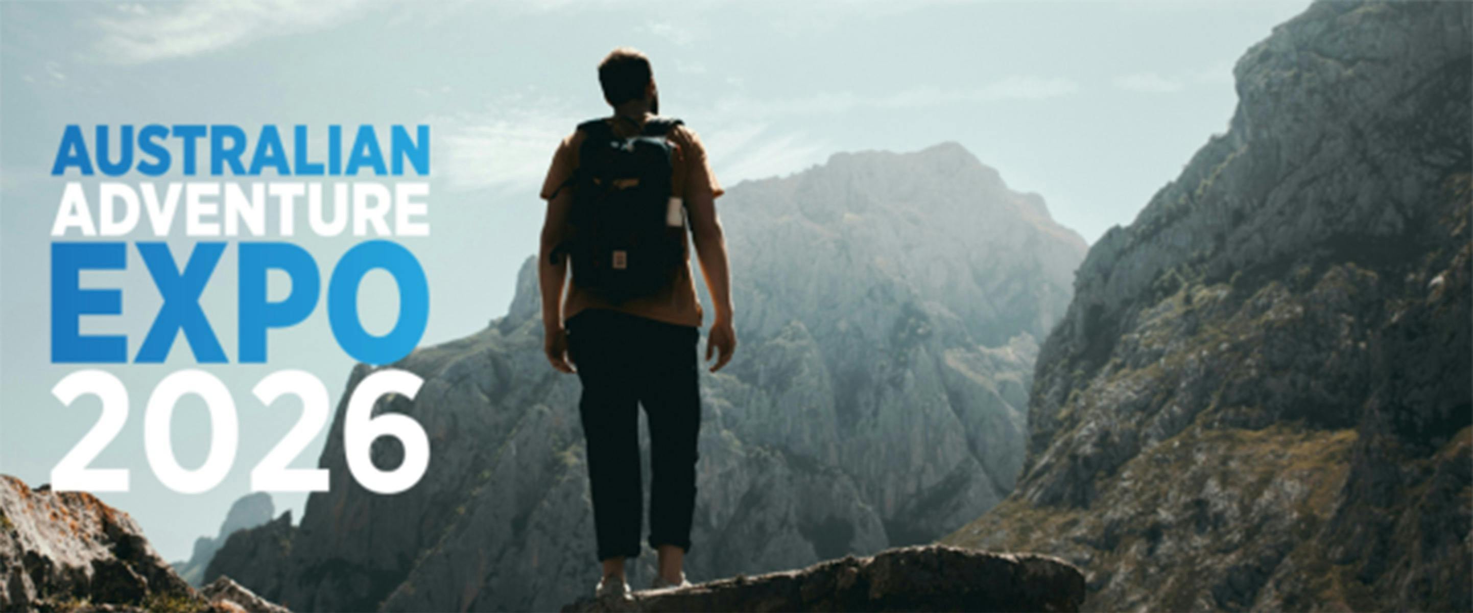 A man wearing a backpack standing on a mountain observing the view.