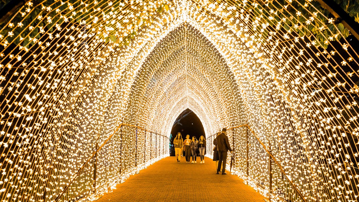 A group of people walking underneath a tunnel of lights