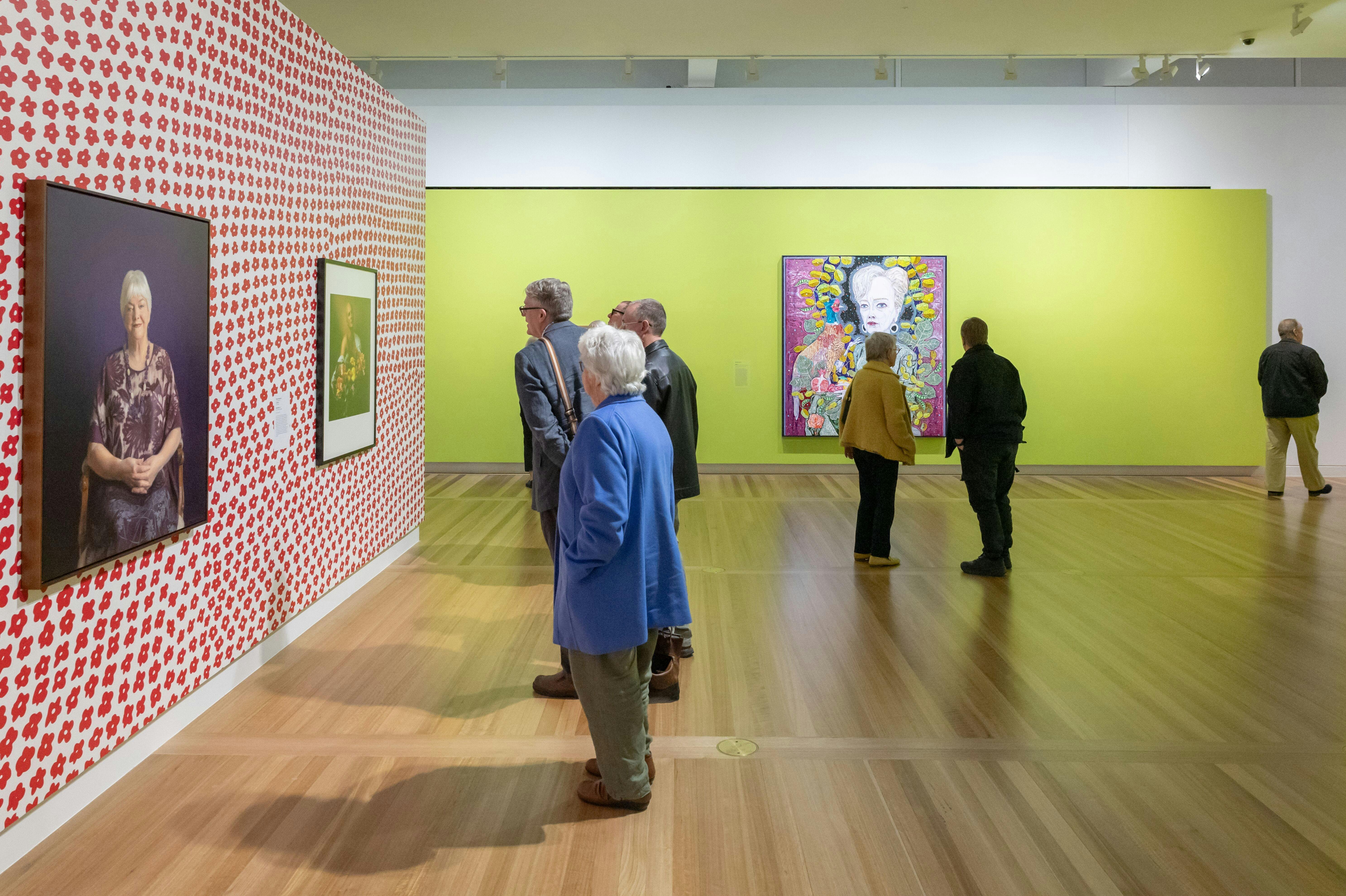 Visitors browse a vibrant gallery space, featuring botanical-themed portraits by Australian artists.