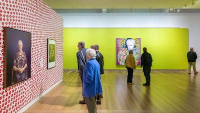 Visitors browse a vibrant gallery space, featuring botanical-themed portraits by Australian artists.