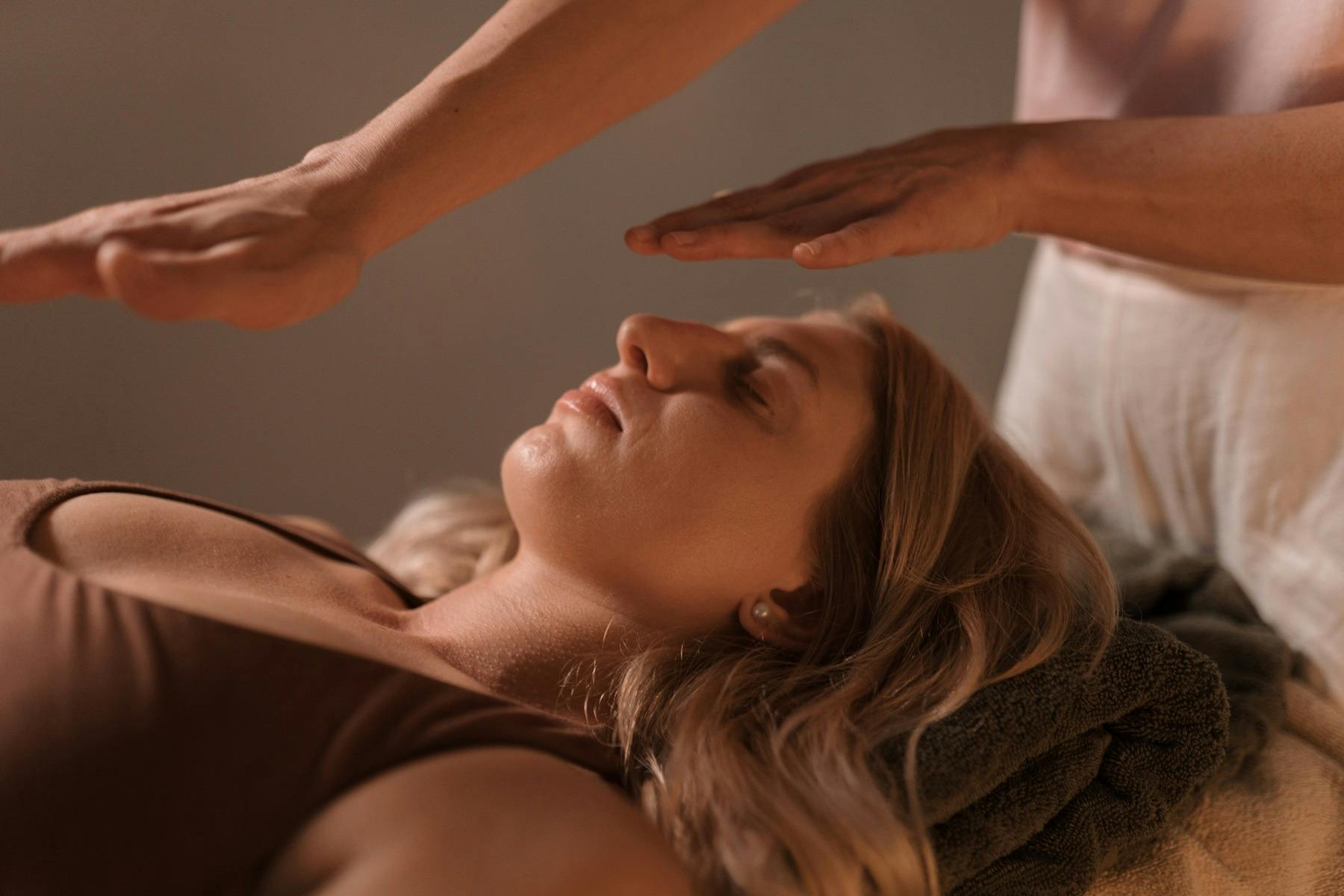 한 여성이 평화롭게 누워 있는 가운데 수행자가 그녀의 몸 위에 손을 올려놓고 에너지를 흐르게 합니다.
