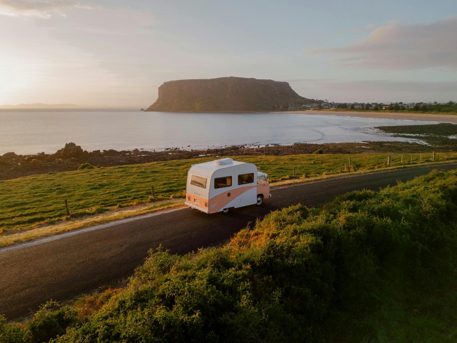 A pink retro RV drives along the coast in Tasmania