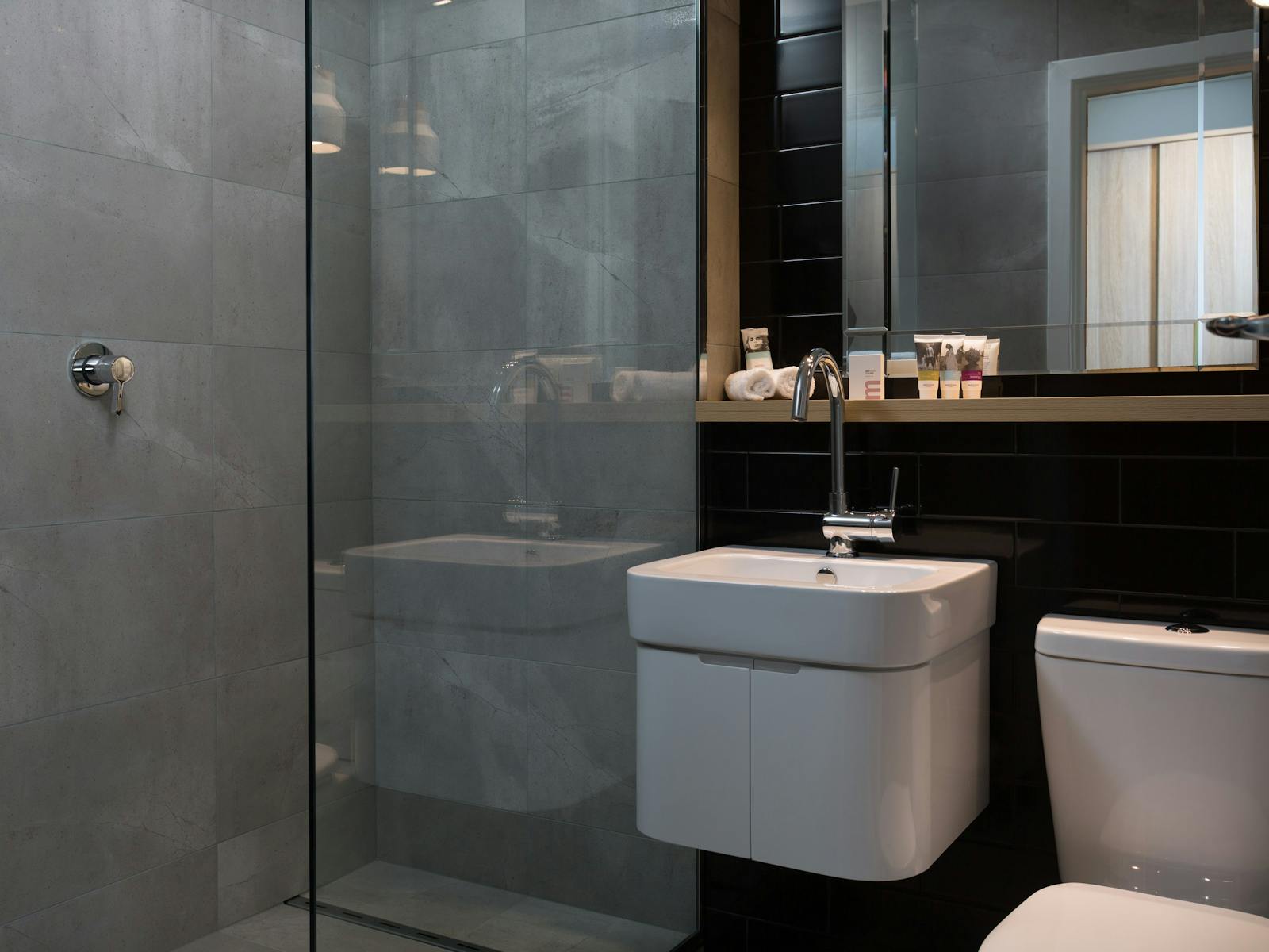 Modern bathroom, showing shower, toilet, hand basin and mirror.