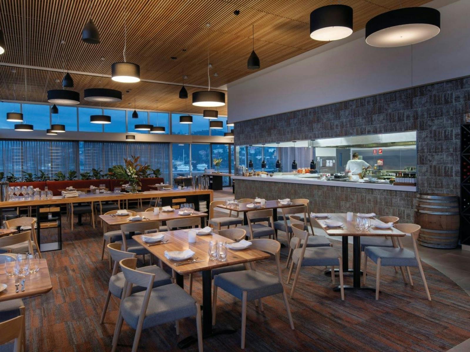 Interior of Grain of the Silo restaurant with a view of the open kitchen & tables set for dinner