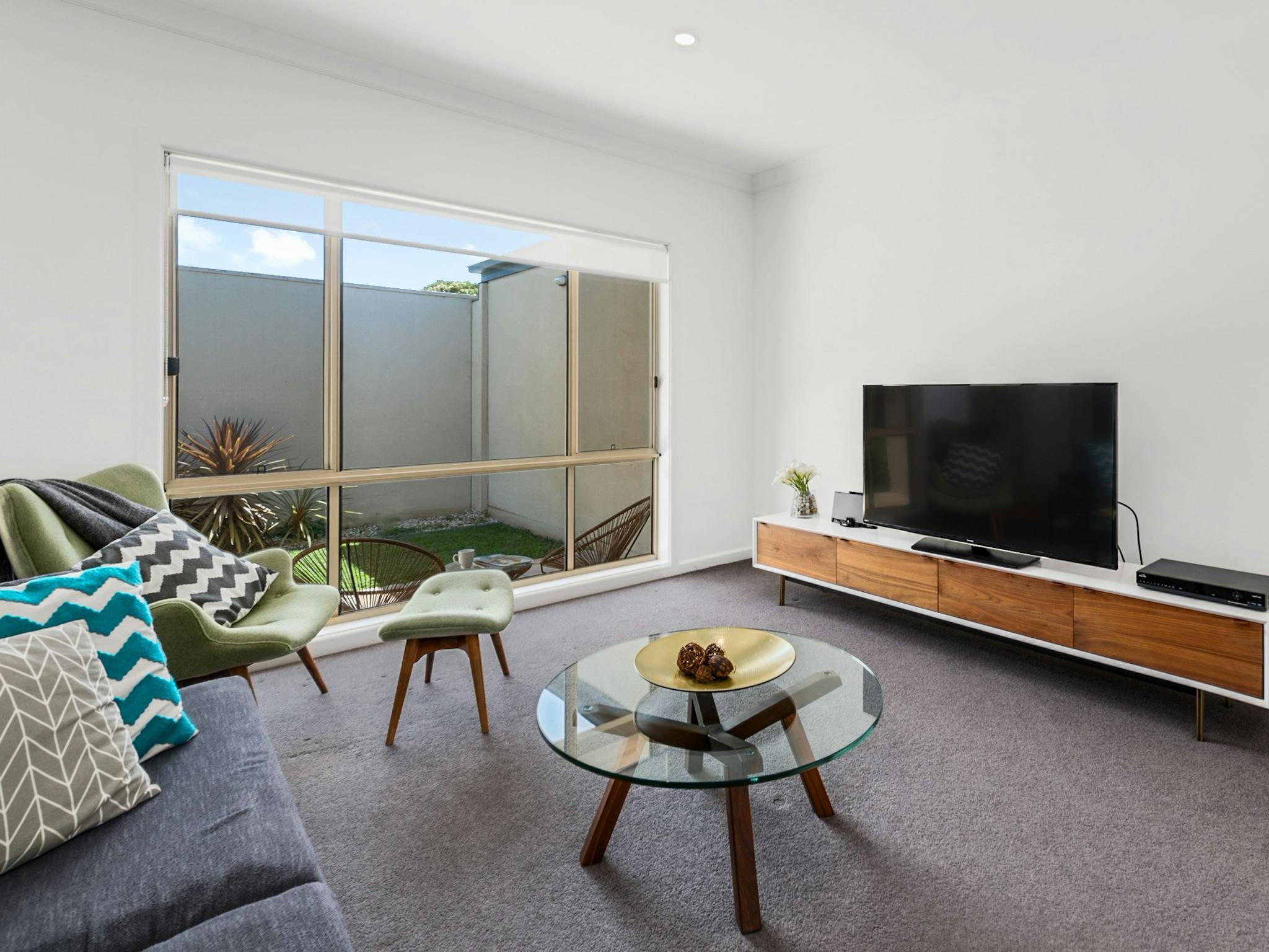 Relaxed living space looking out to courtyard with sofa, chair and television