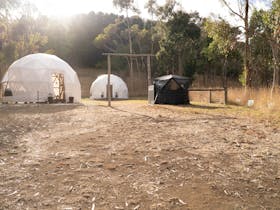 Two white geodesic domes and a black tent structure that is our wood fire sauna.
