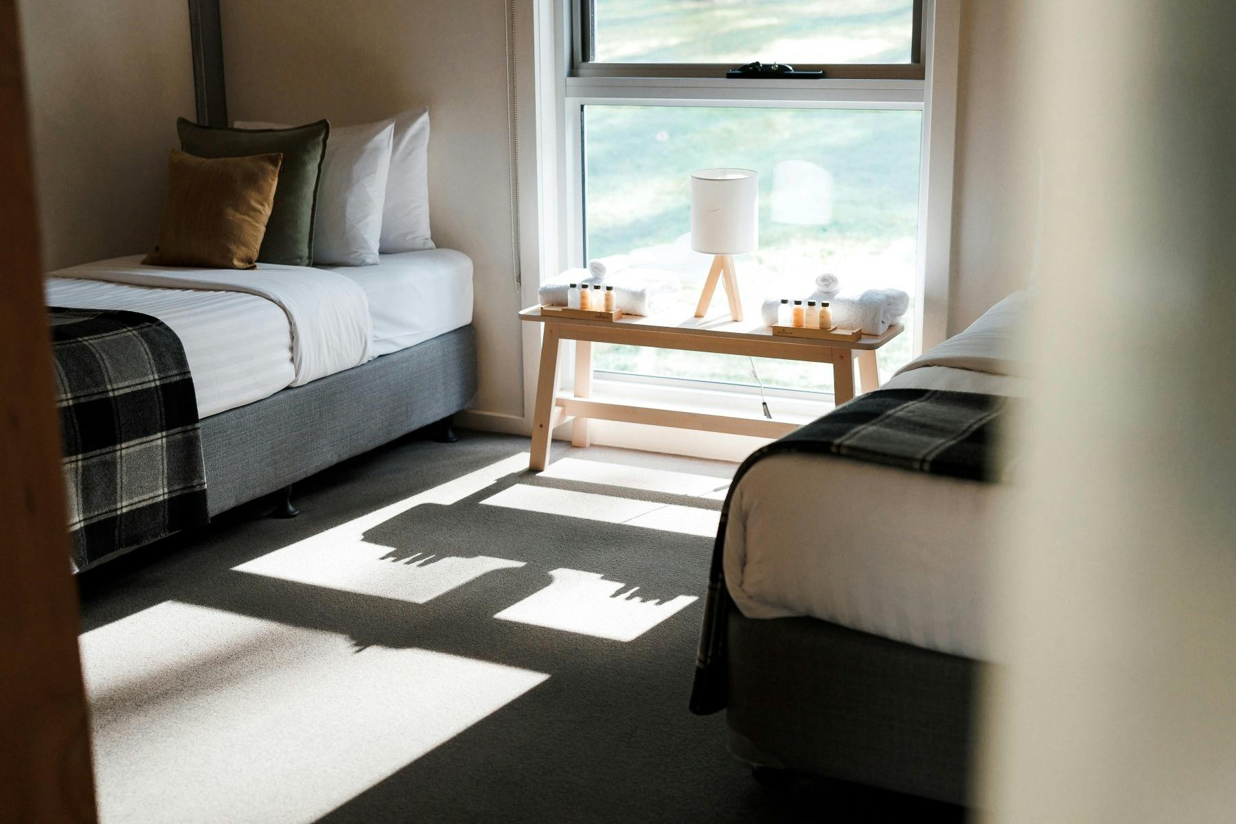 Cosy bedroom with two single beds and window in between with views of bushland