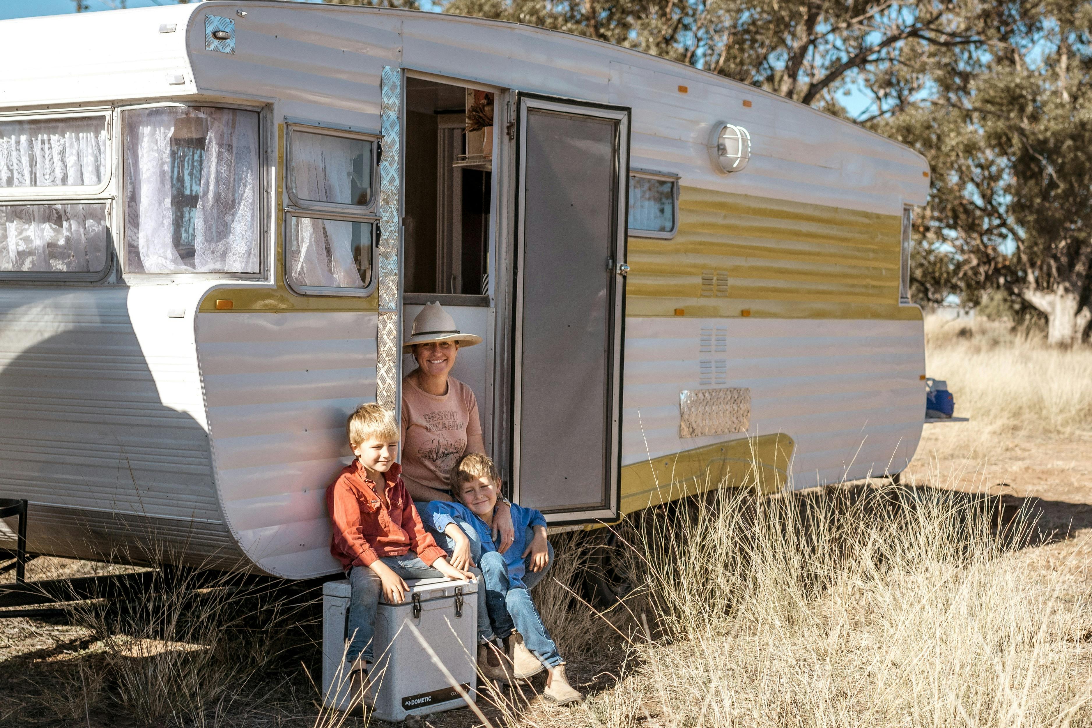 A family sitting in their Caravan at the Gilgooma camp ground farm stay in the rural paddock setting