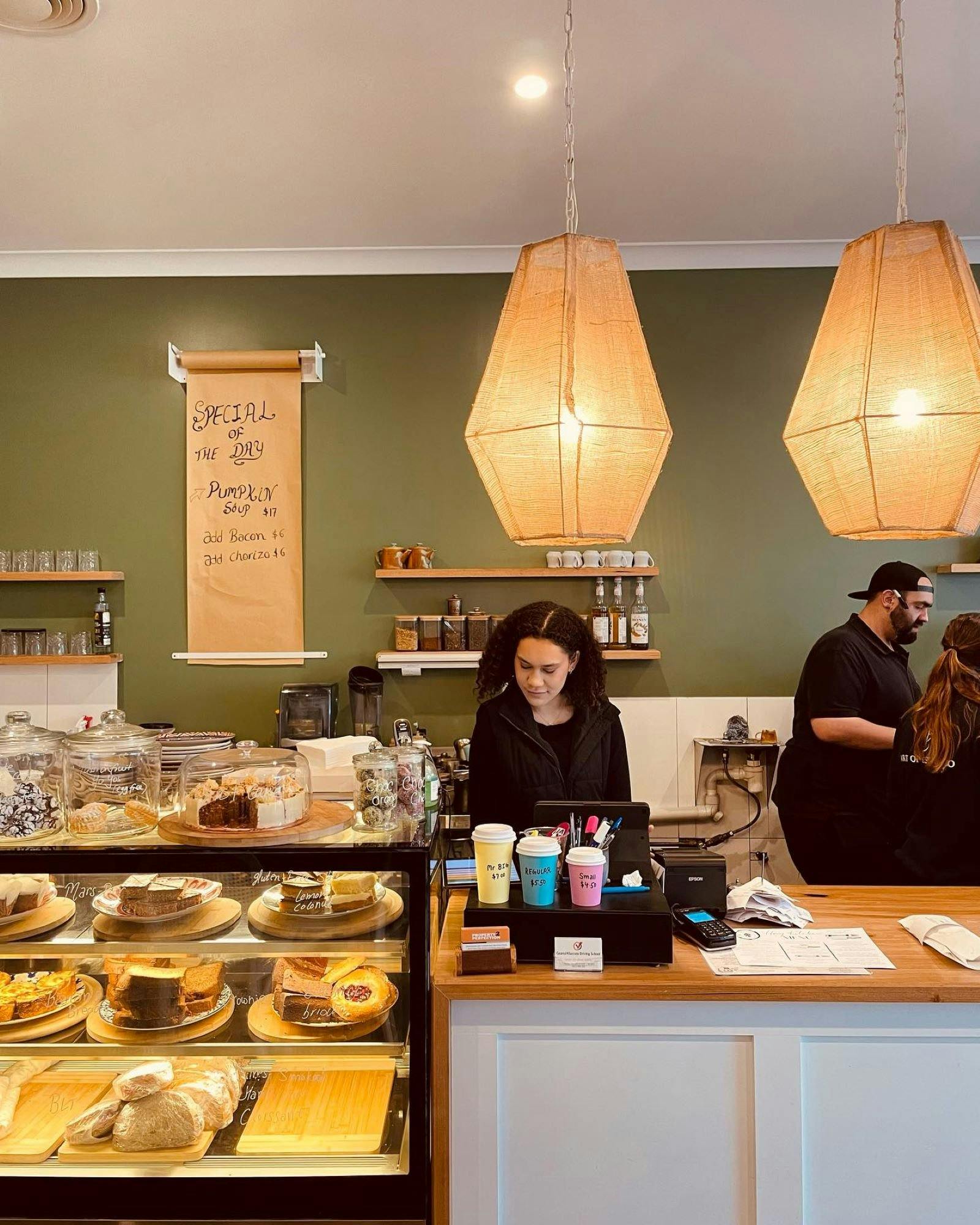 Barista and front desk area with a cafe display full of goodies.