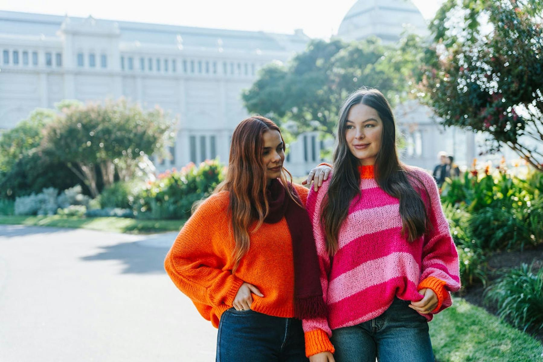 Two women, one wearing an orange jumper and one wearing a pink striped jumper