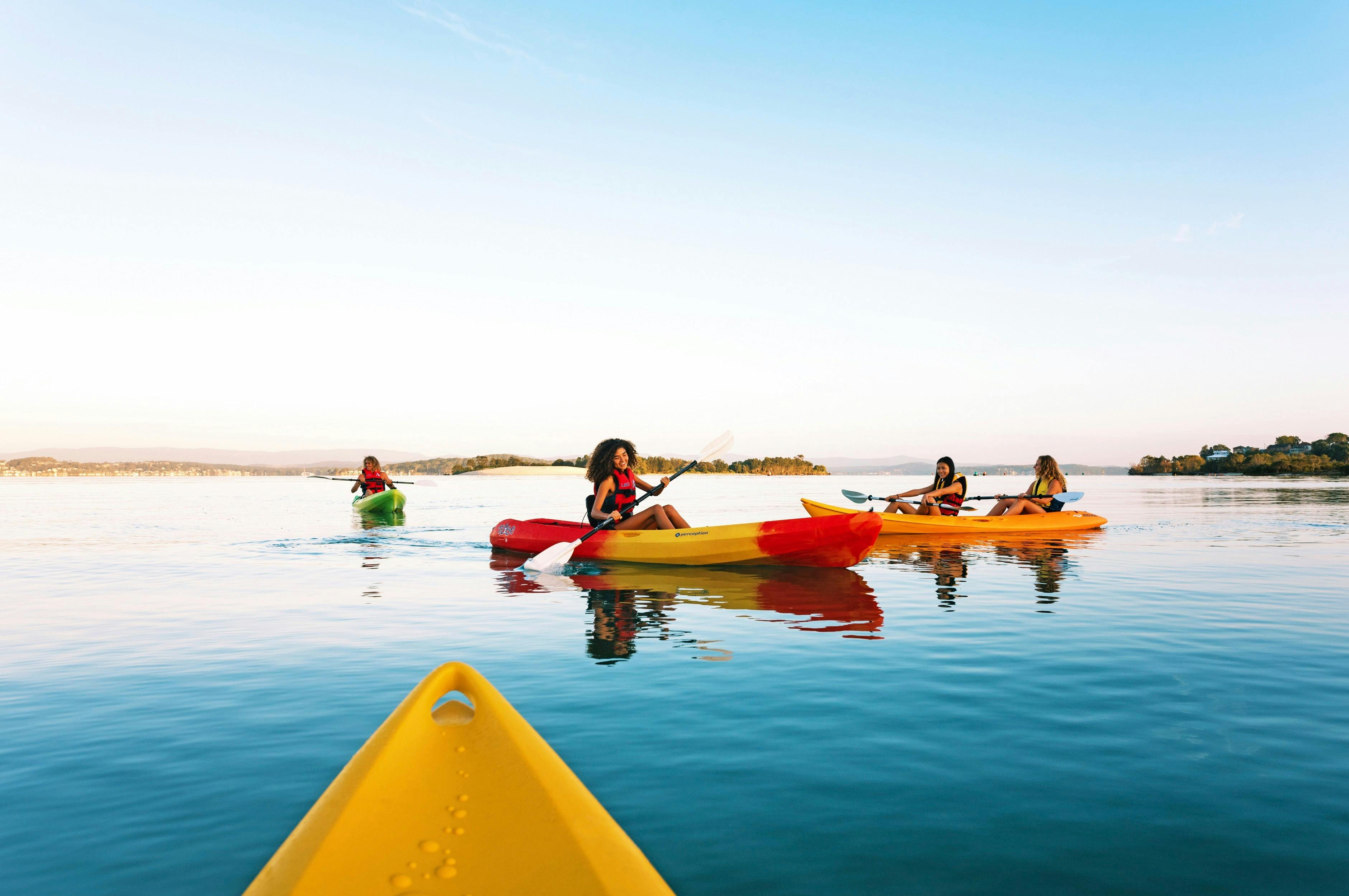 Friends enjoying a day of kayaking on Lake Maquarie off Naru Beach