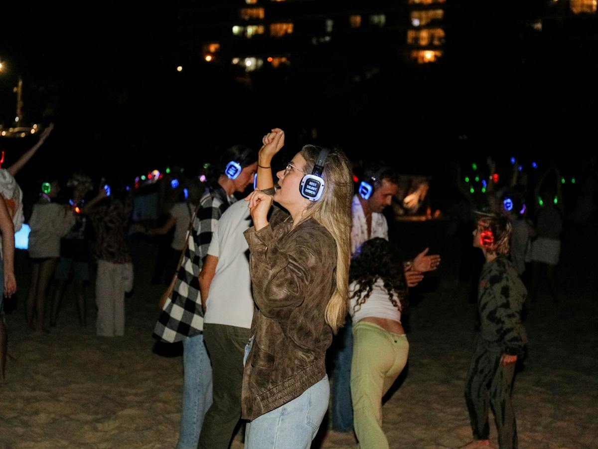 100's of people dancing on the beach atSilent Disco Under the Stars at SWELL Sculpture Festival 2024