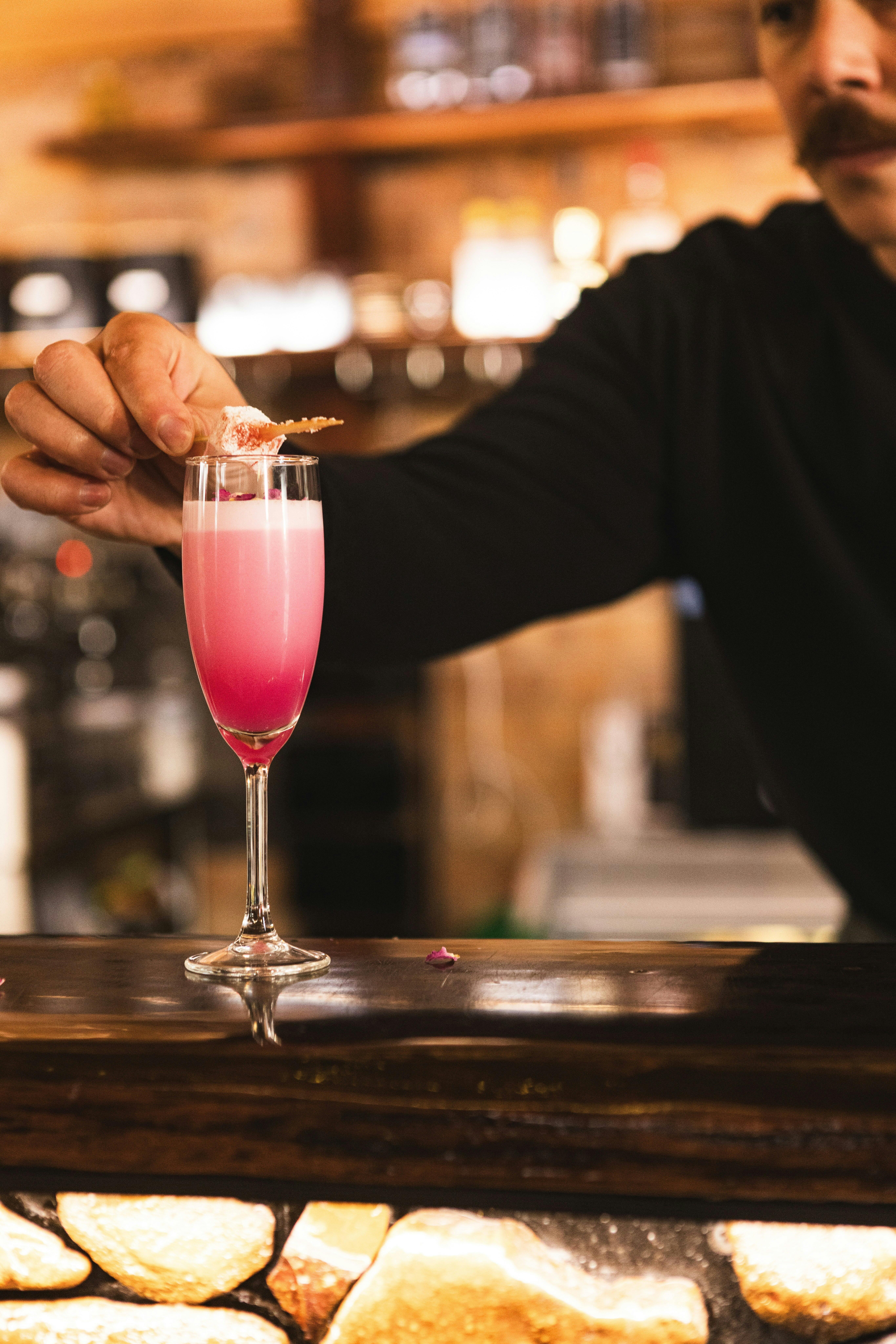 pink cocktail with hand placing garnish
