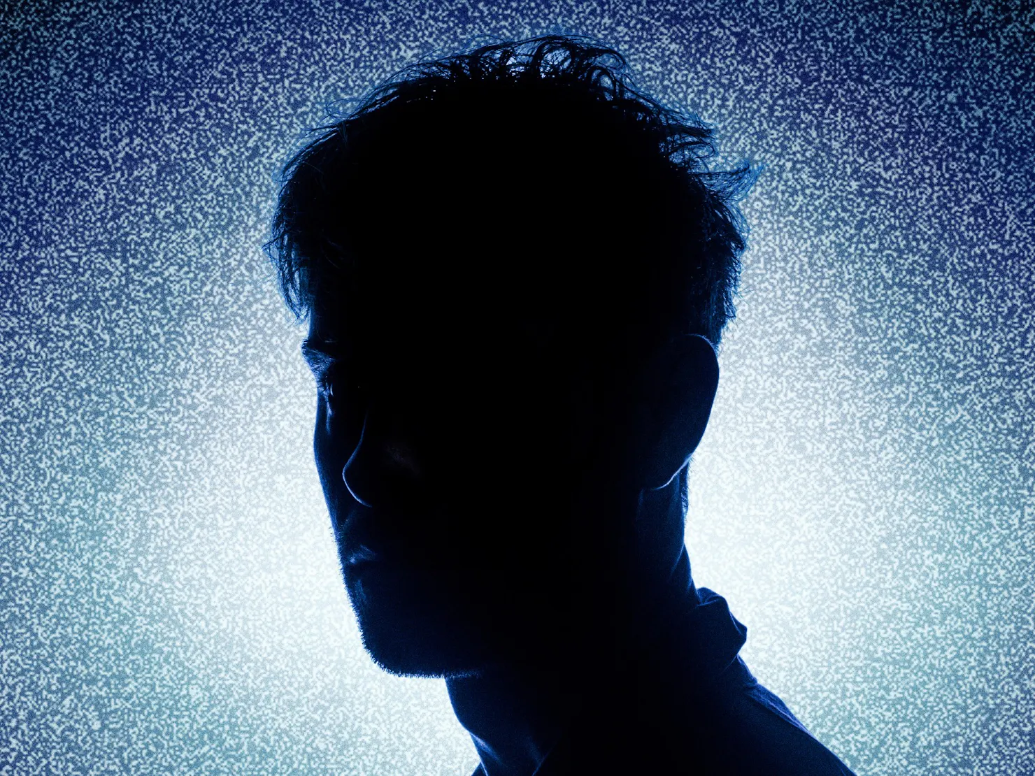 A Silhouette  of a man against a dark blue background.