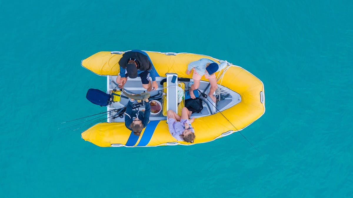 Four people fishing in a dinghy, in the Whitsundays.