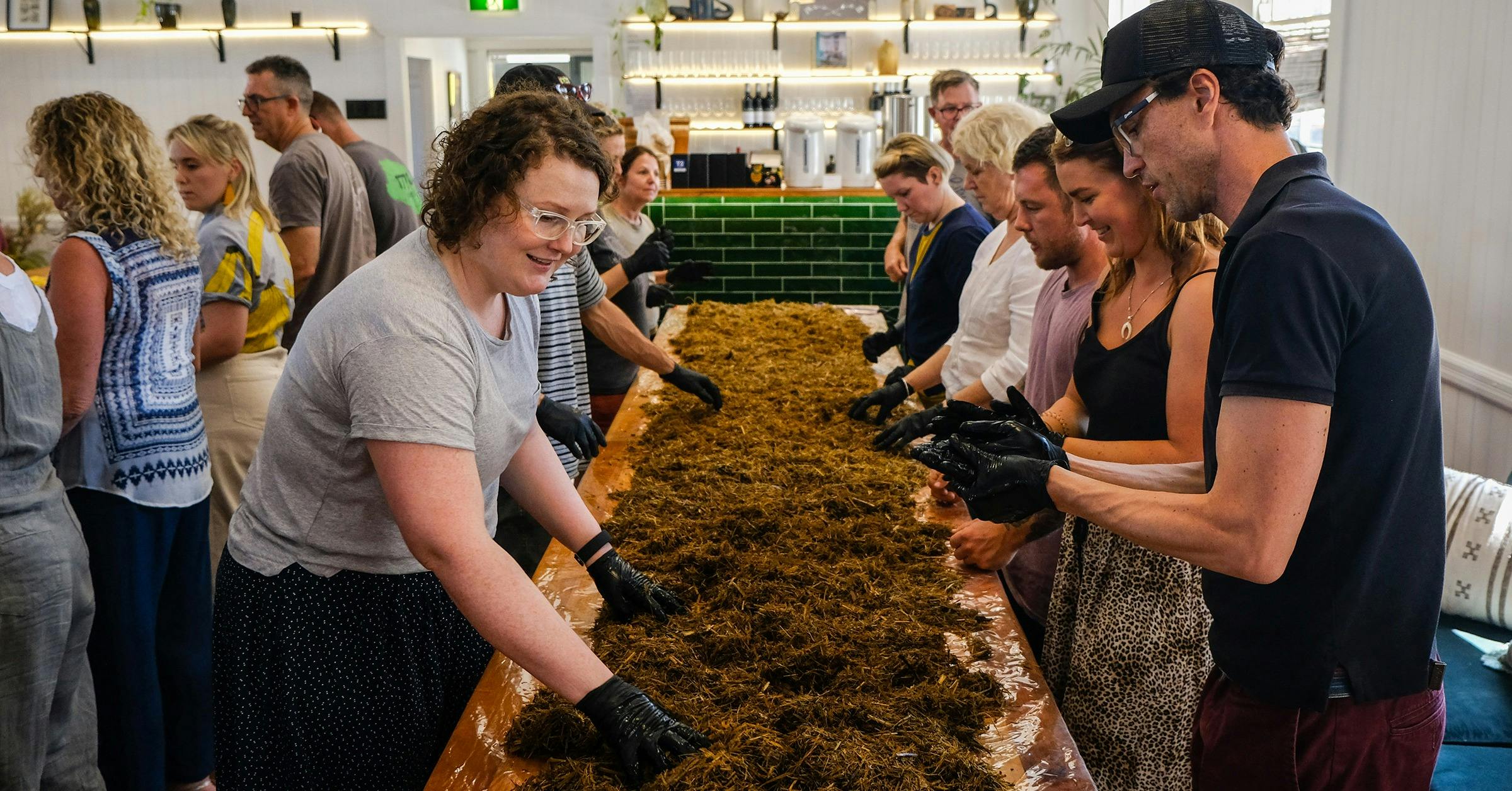 group of people with their hands in mushroom substrate spreading mushroom spawn at little acre