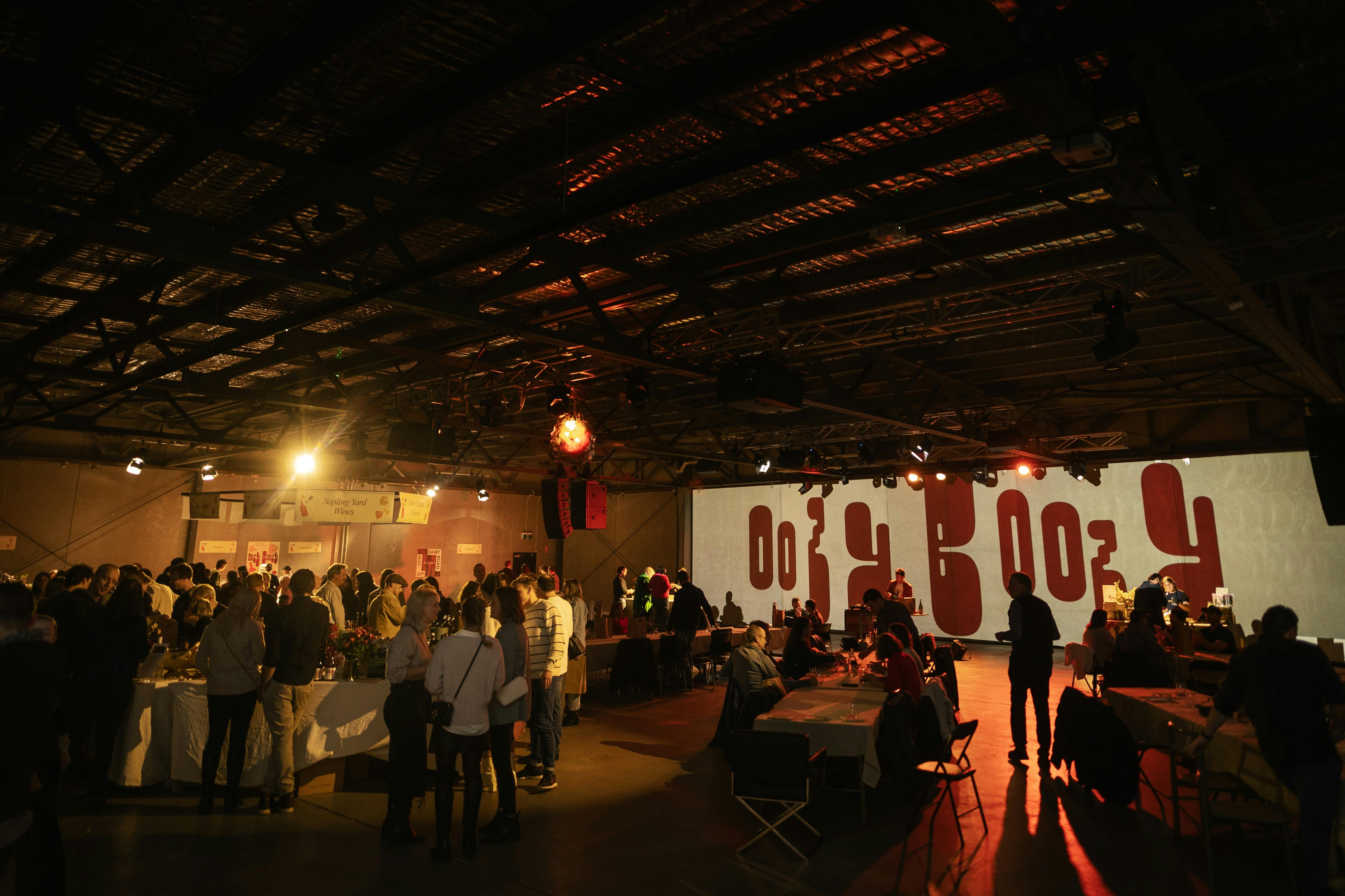 Large indoor space with cheese and wine stalls and seating with lots of people