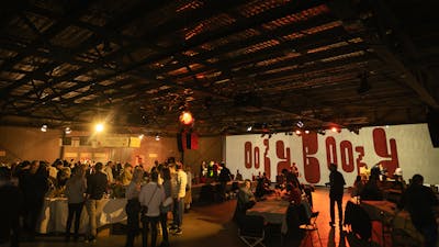 Large indoor space with cheese and wine stalls and seating with lots of people