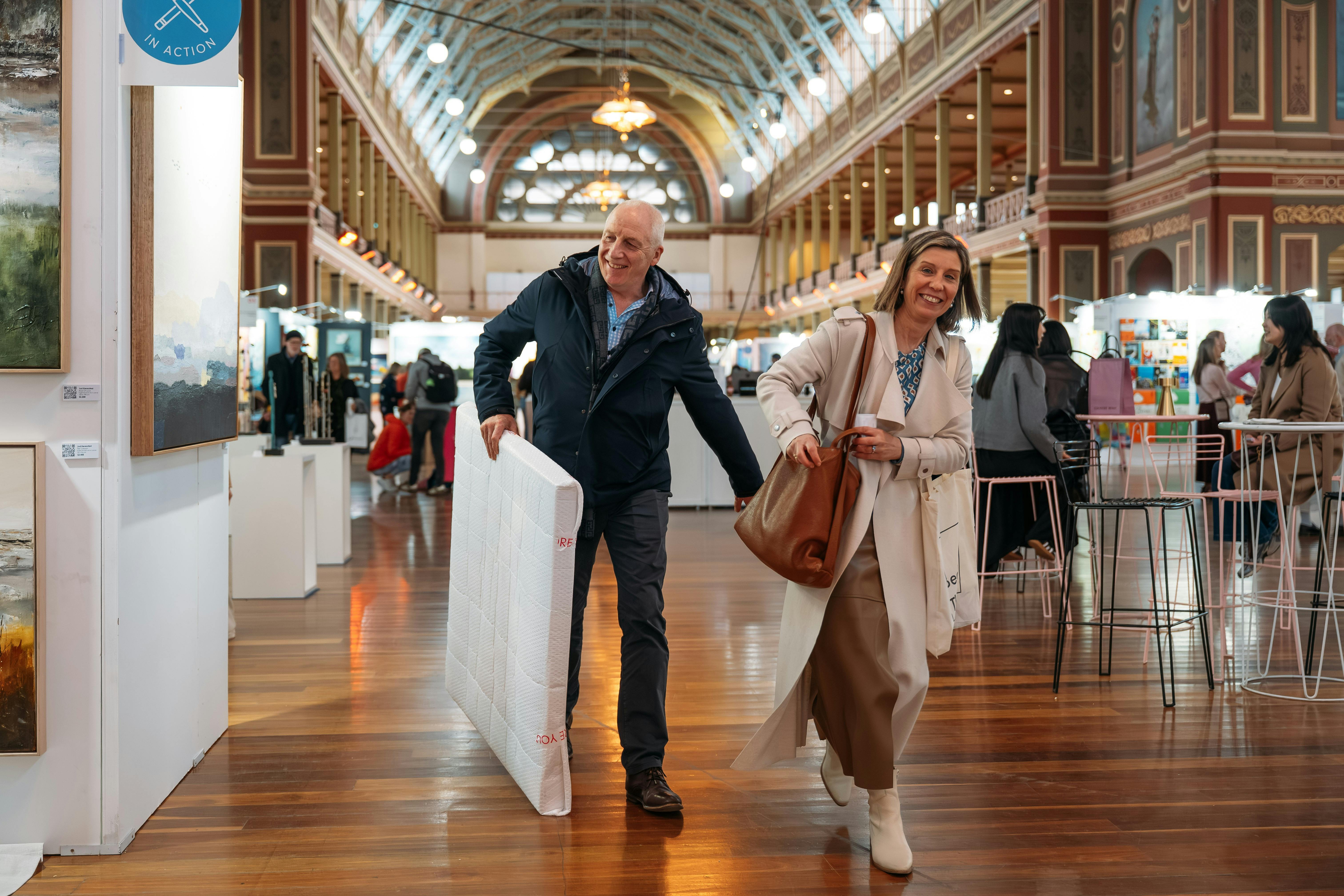 Image of two visitors walking with artwork in their hands
