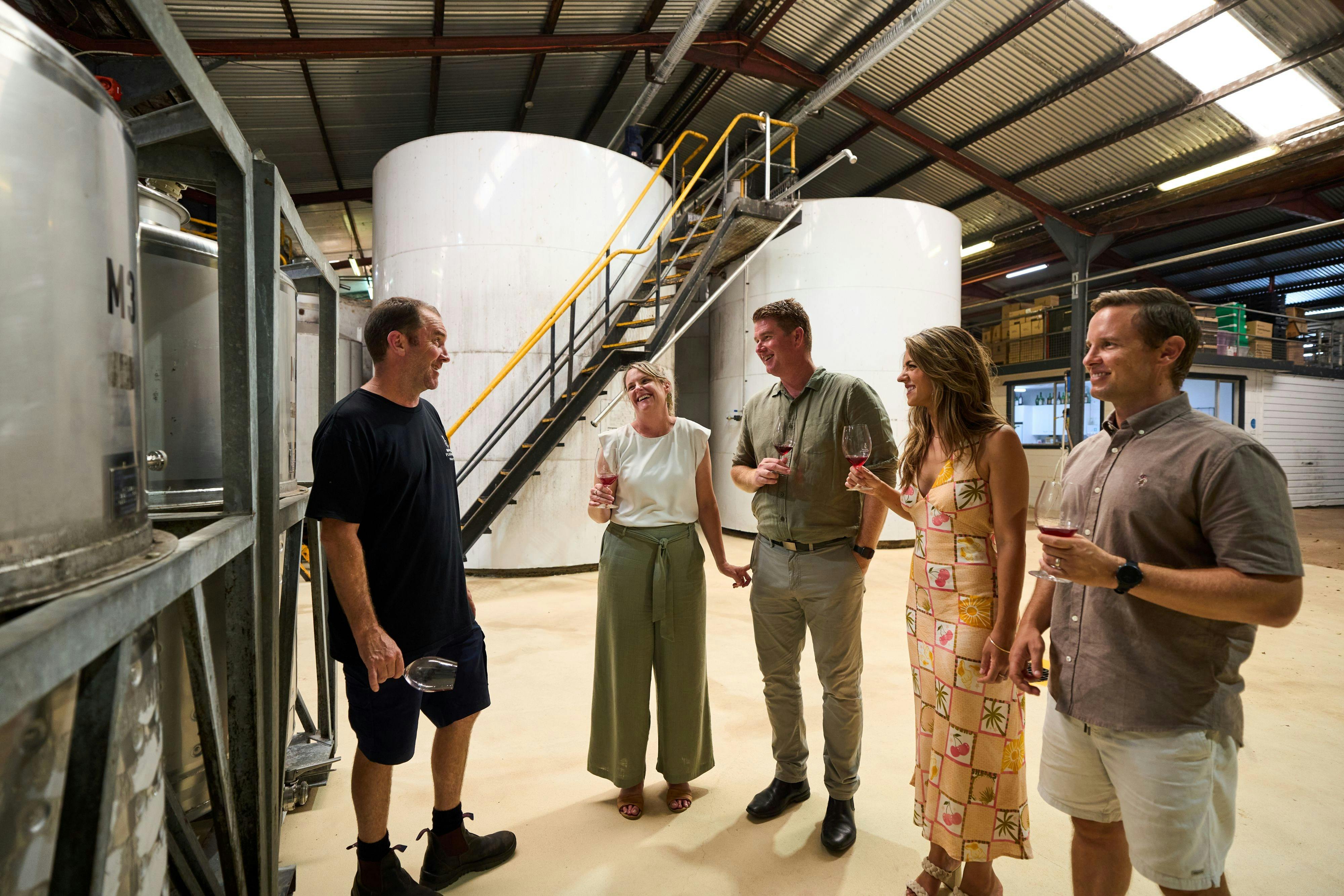 Guests touring a winery among the stainless steel wine tanks with their guide