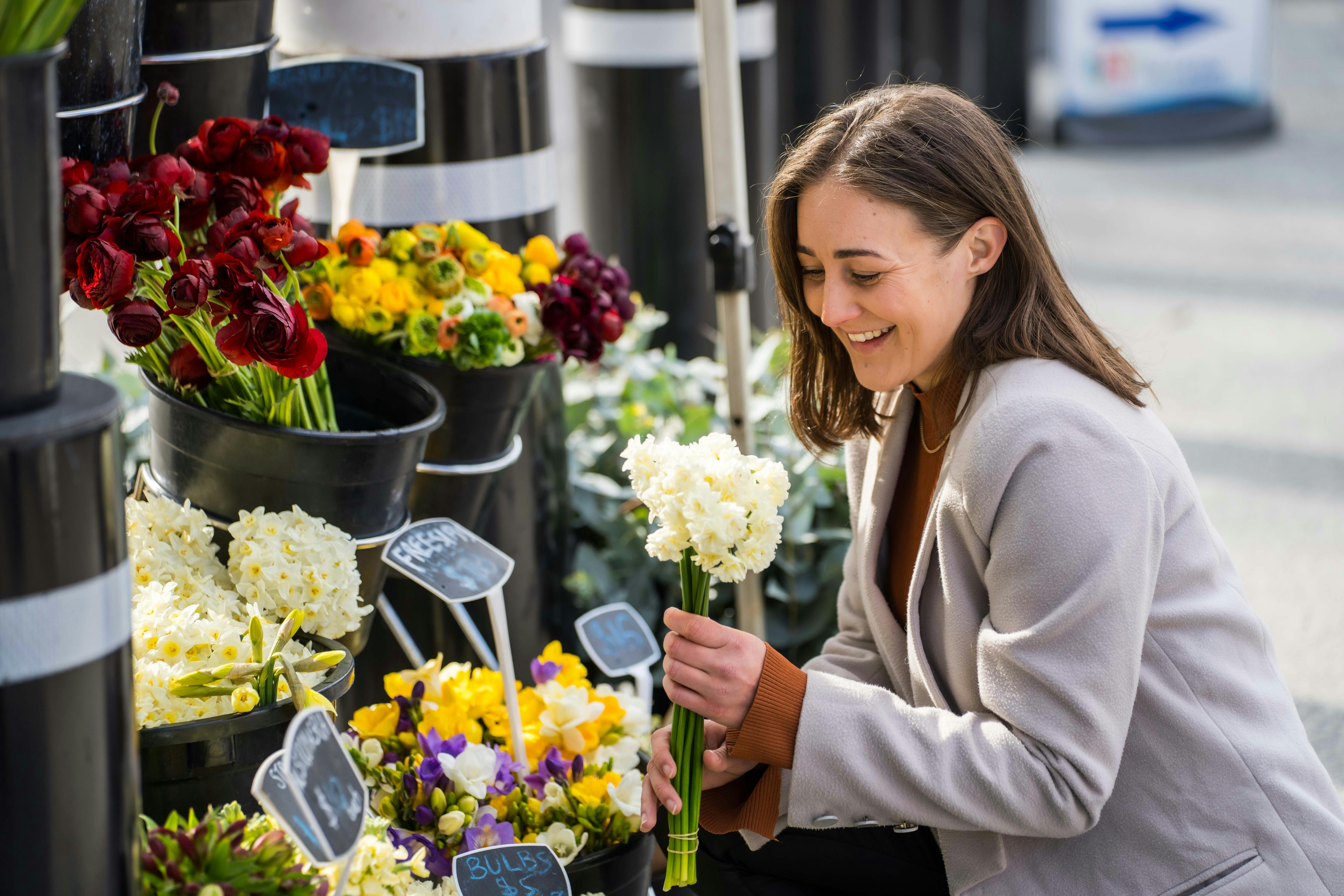 A girl chooses some fresh daffodils from the maket