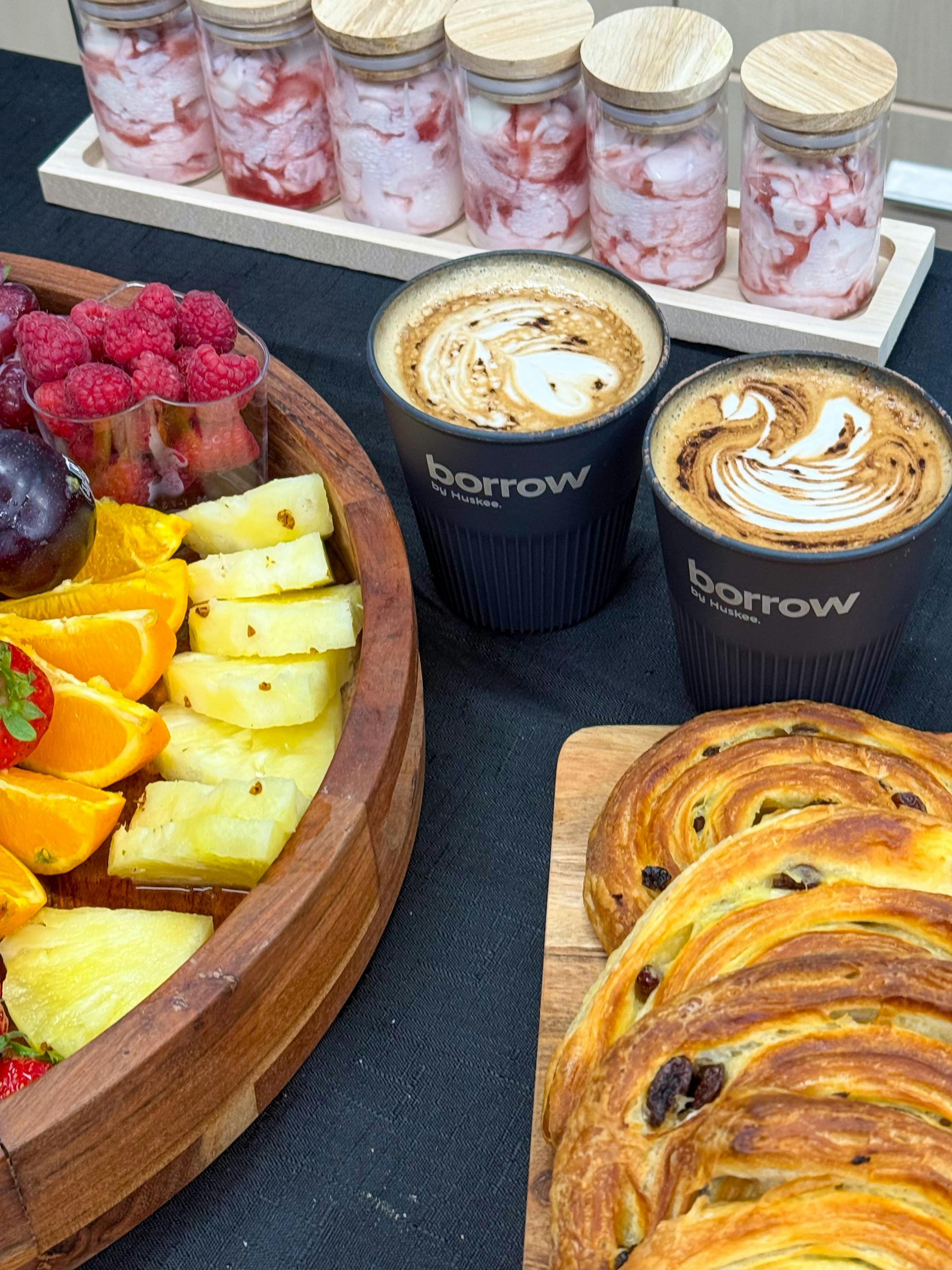 Fruit, pastries and Pure Bean coffee in Huskee Borrow cups with latte art displayed for paddlers .