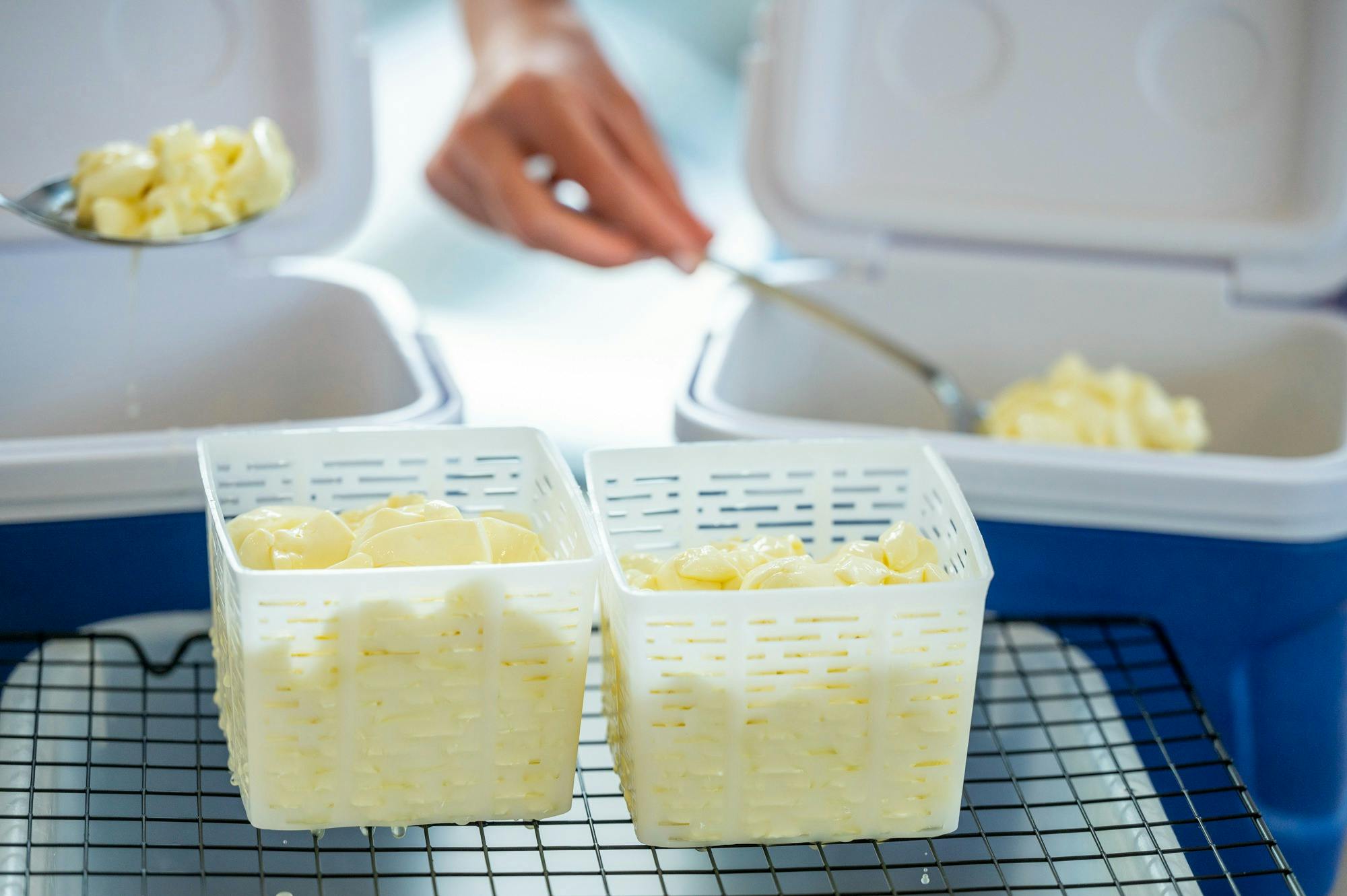 Hands scooping curds into baskets
