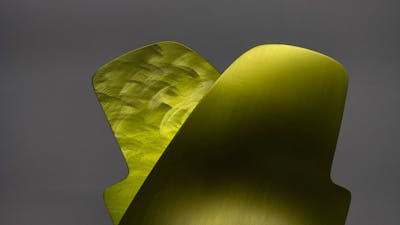 A lamp made from a thin sheet of folded burnished metal in an abstract shape.