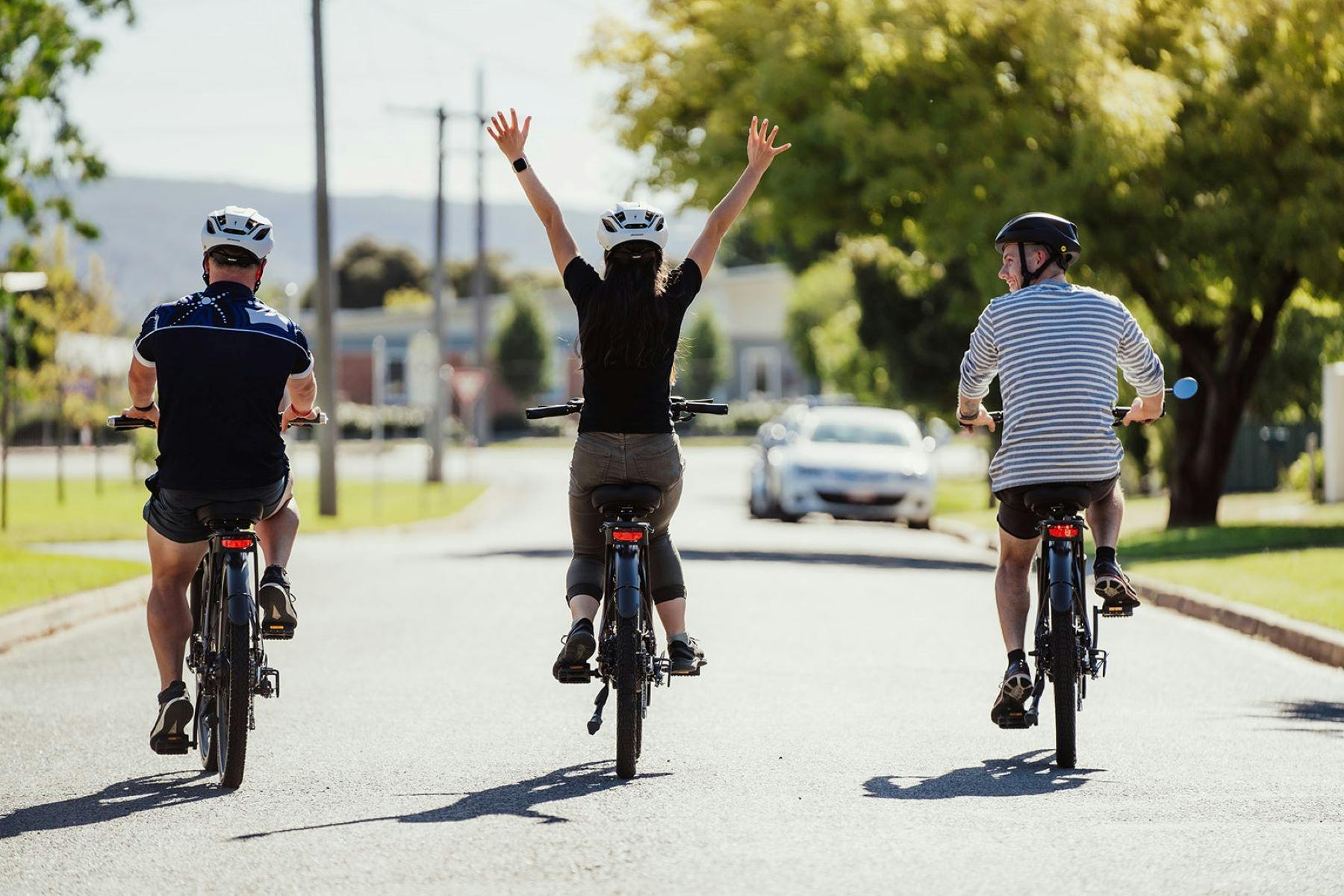 Three people riding bikes with backs to camera