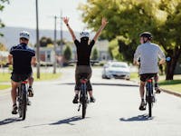 Three people riding bikes with backs to camera
